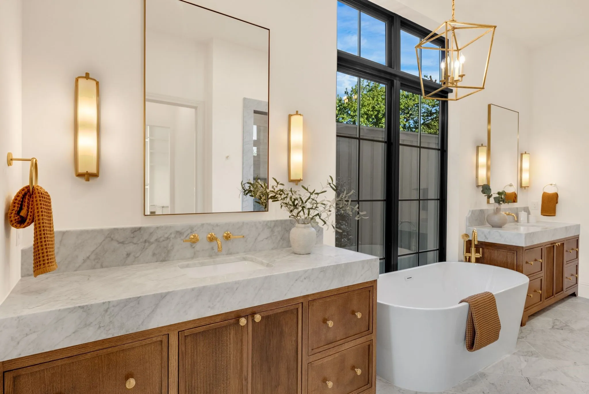 Dual floating vanities with marble countertops, an undermount sink, and wall-mounted brass faucets