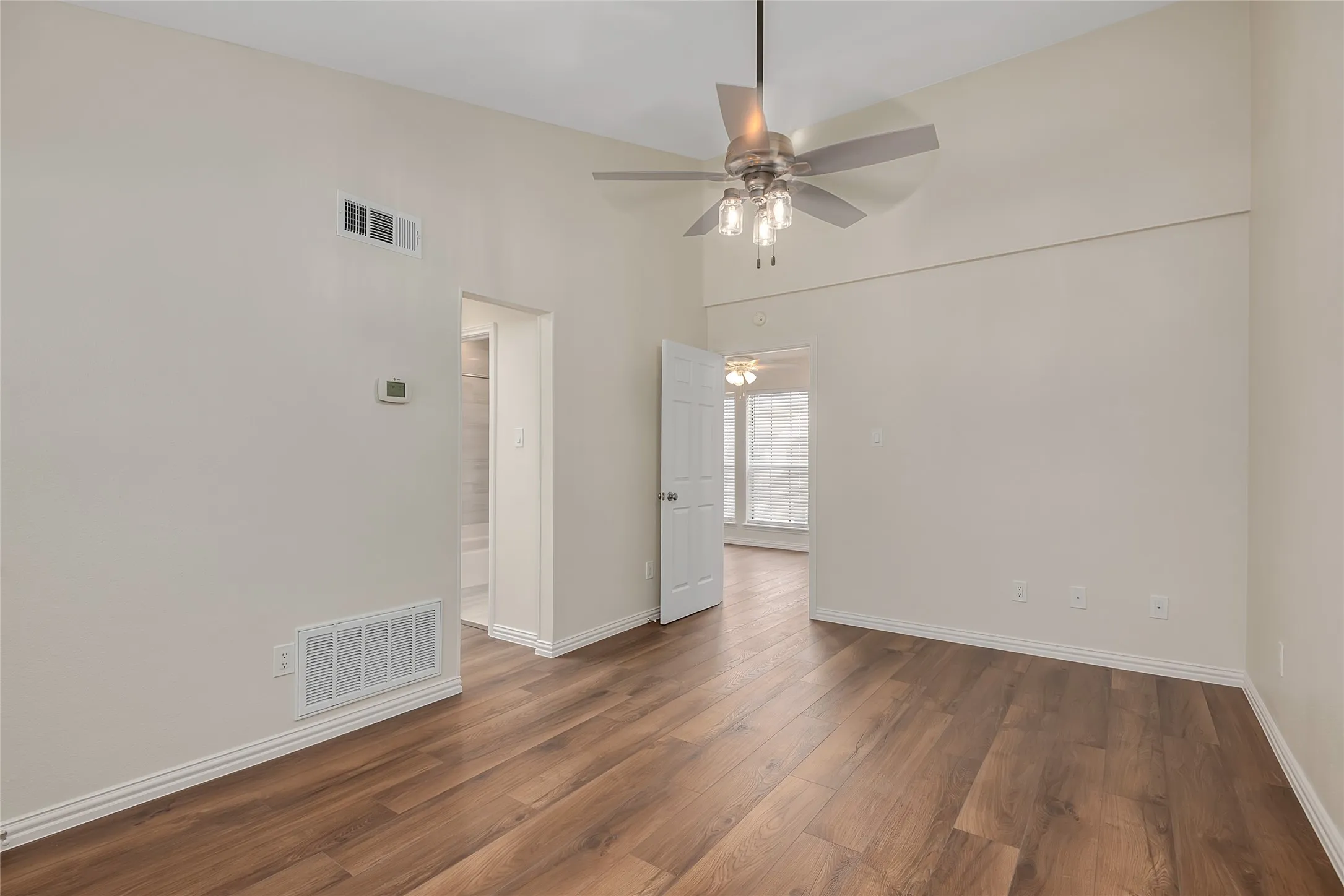 Vaulted ceiling with a ceiling fan, wood-finish flooring, and white trim