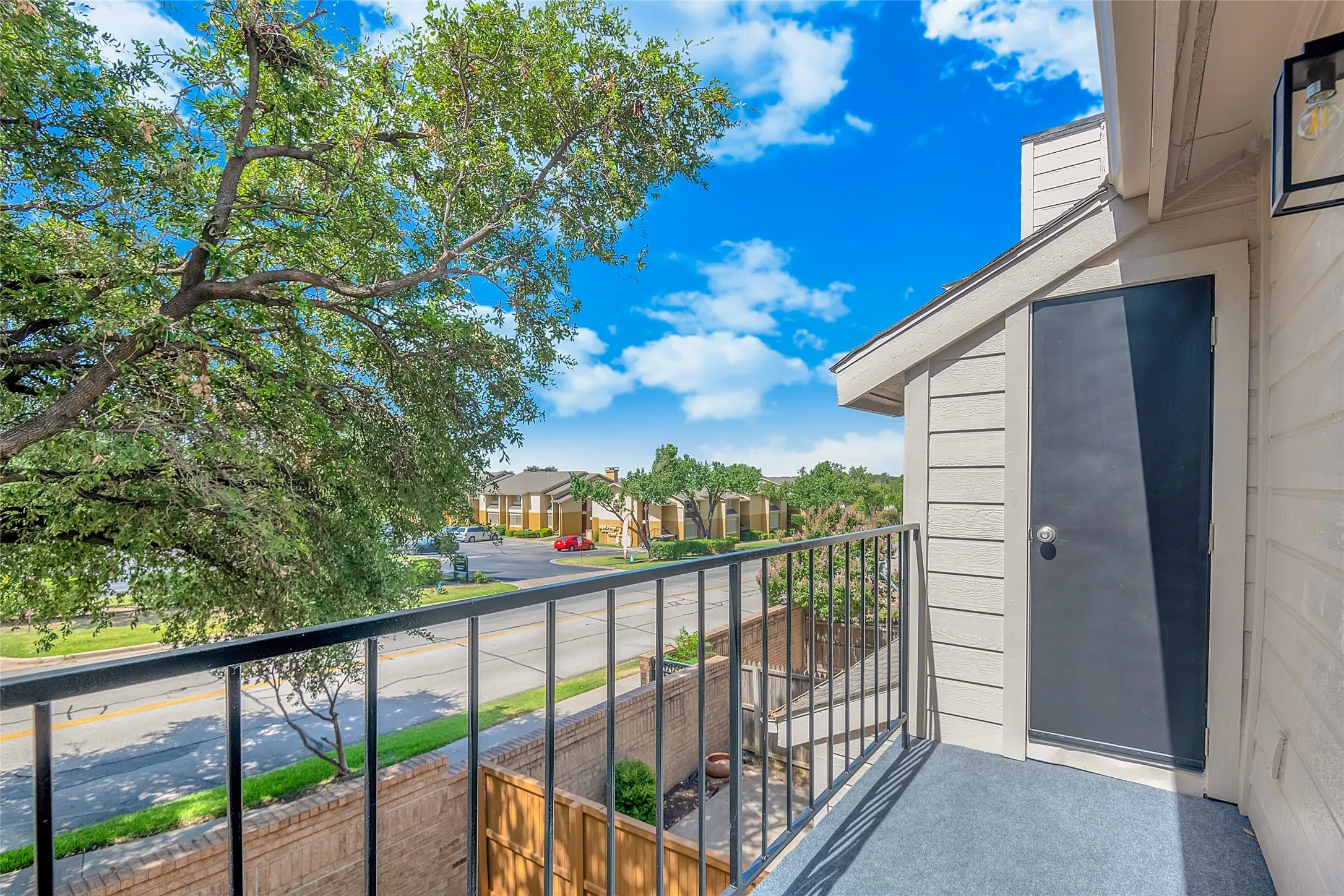 Balcony featuring black metal railing, grey outdoor carpet, and exterior storage closet
