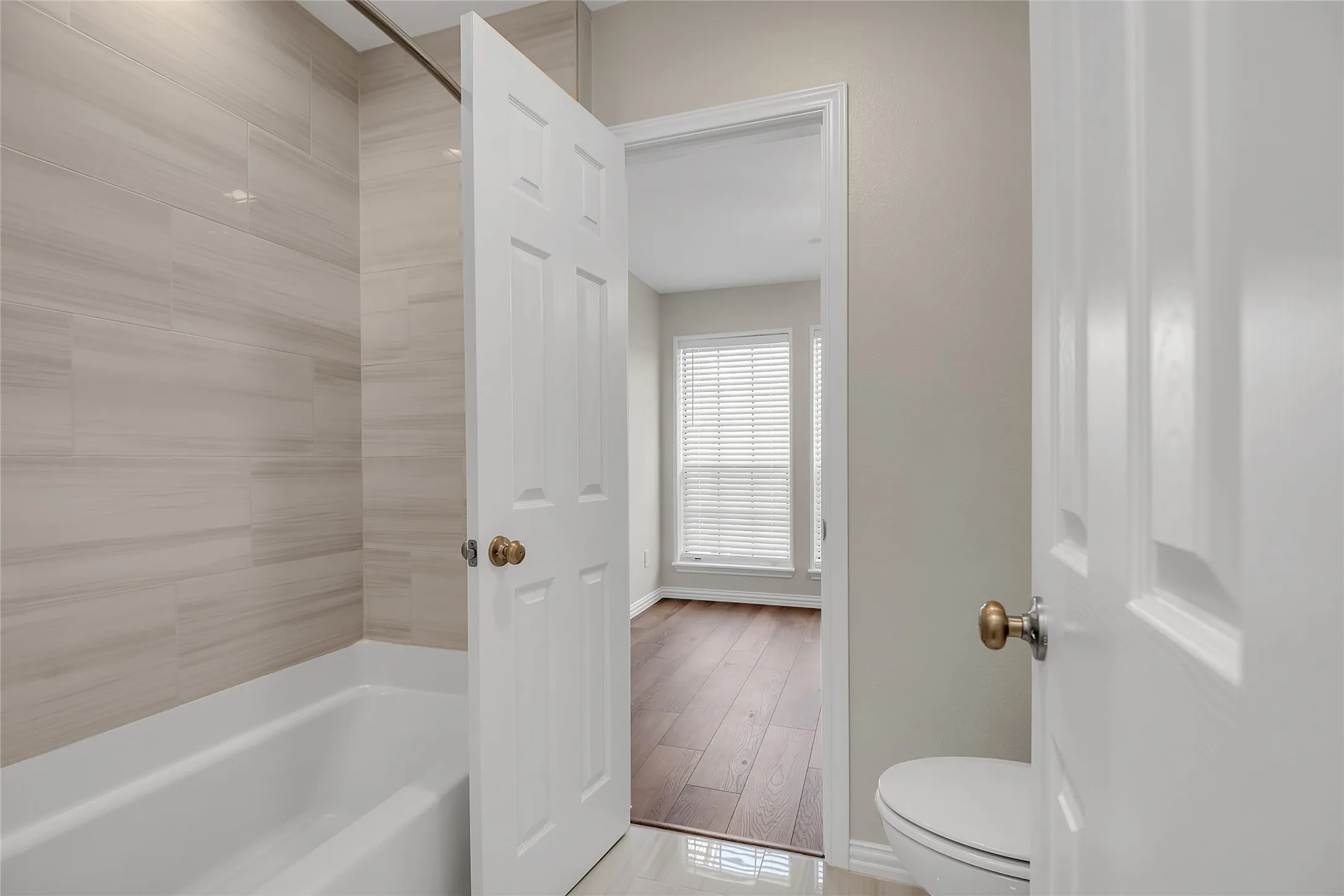 Bathroom featuring a white bathtub, light-toned tiled shower surround, and a white toilet