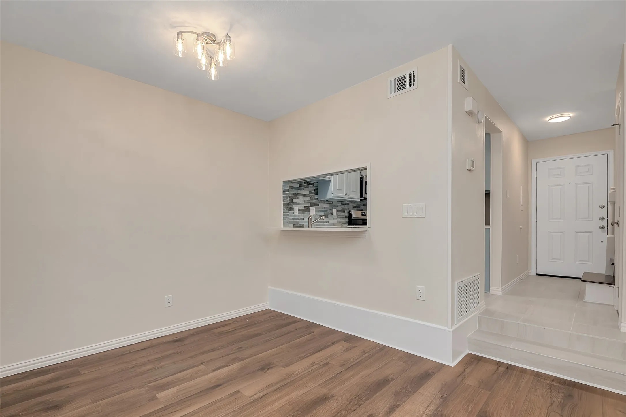 Wood-finish flooring, contemporary chandelier, pass-through kitchen opening, tiled entry, and recessed lighting