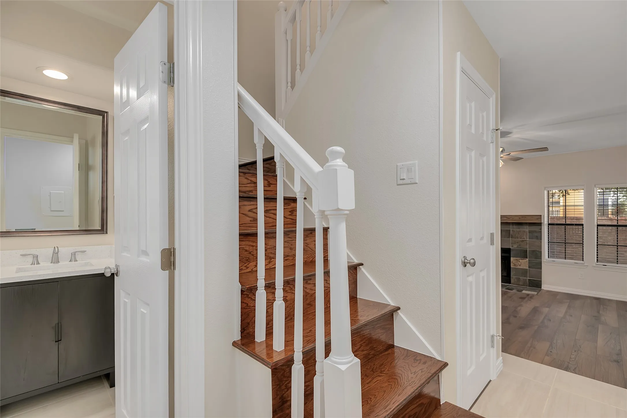 Wood-finish staircase with white balusters, leading to an upper level