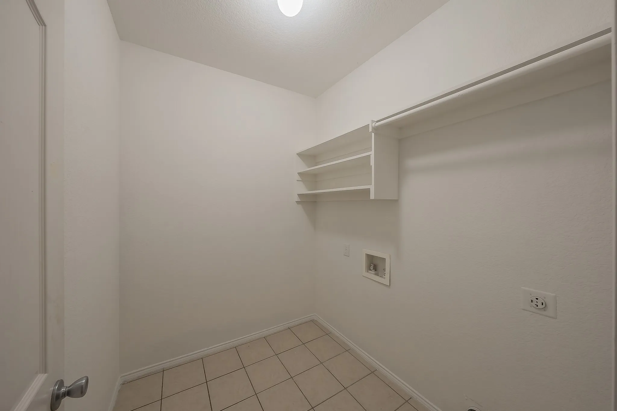 Utility room with tile flooring, built-in shelving, and a clothing rod