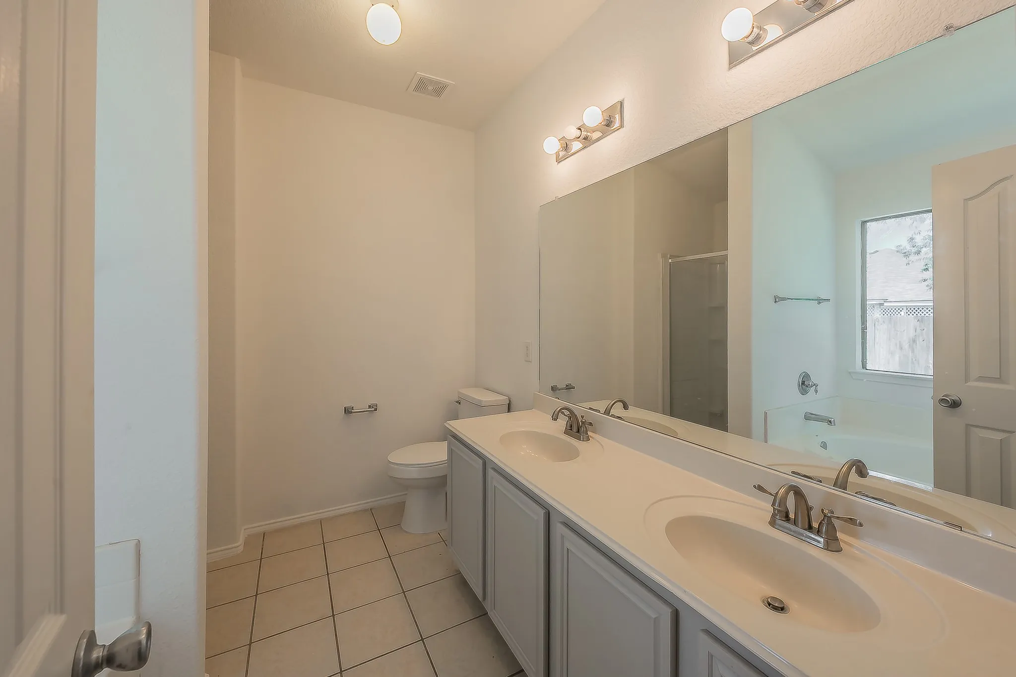 Dual vanity with integrated sinks, brushed nickel fixtures, and a large wall-mounted mirror