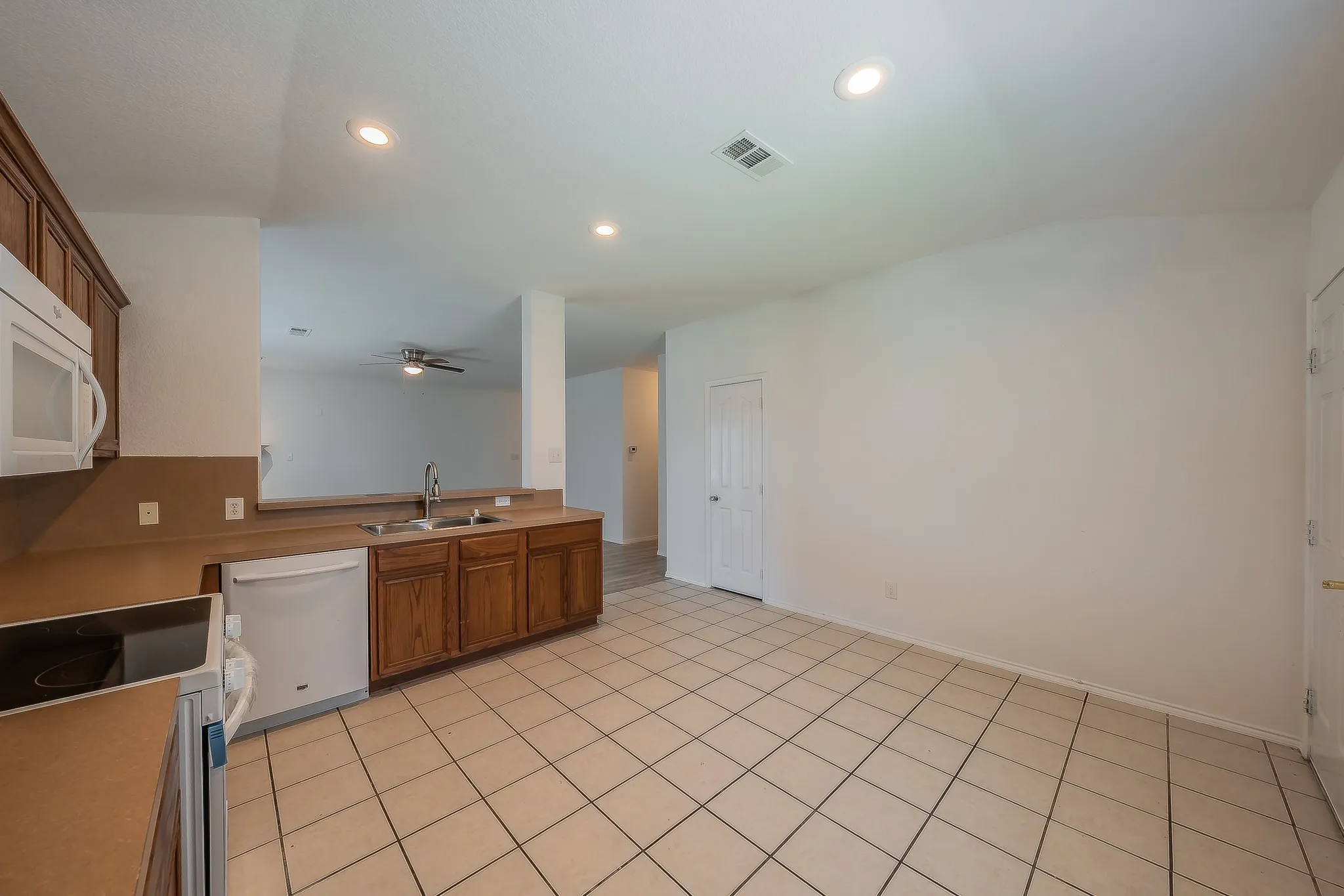 Tile flooring, wood-finish cabinetry, recessed lighting, built-in microwave, and stainless steel sink