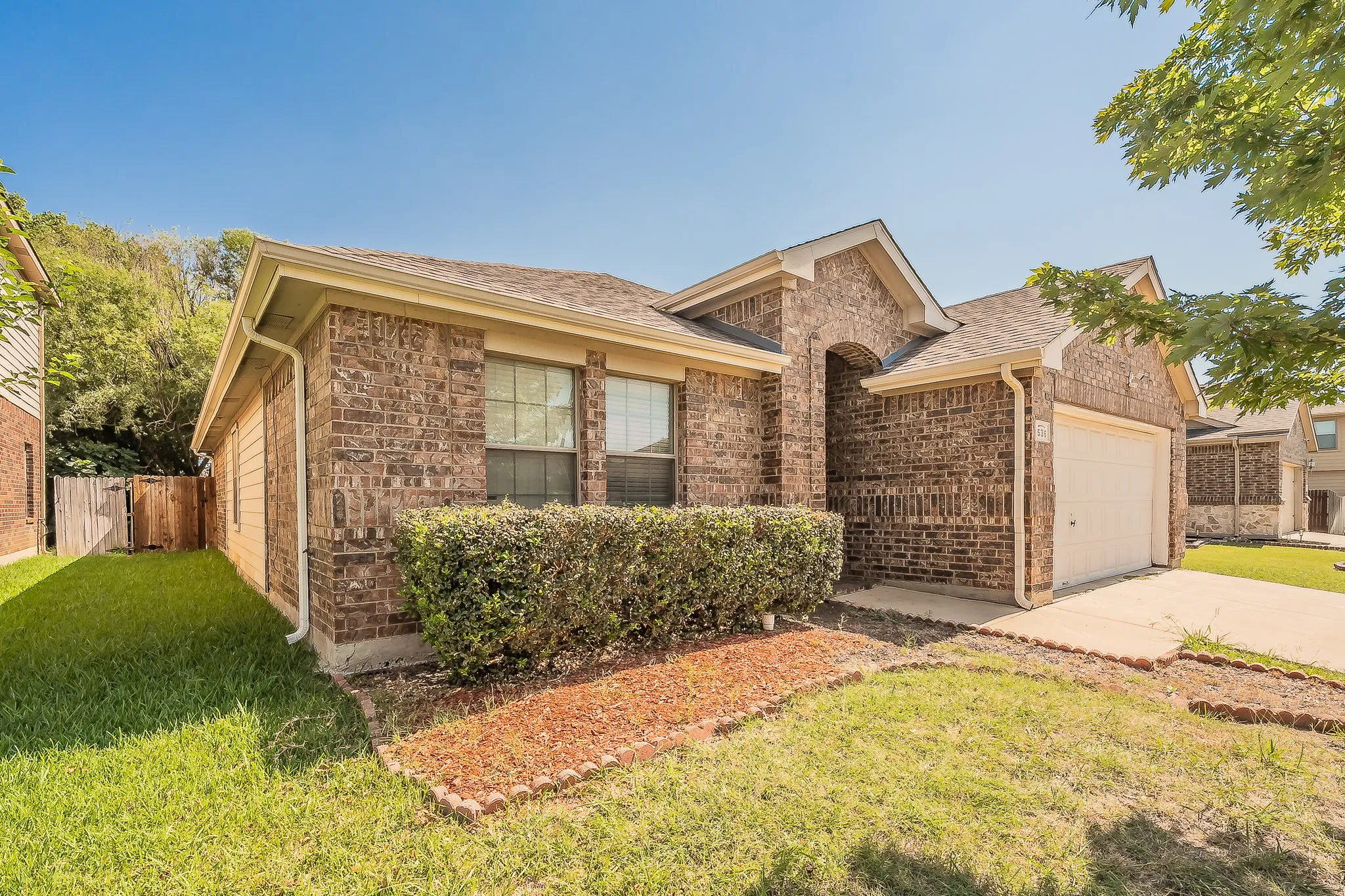 Brick exterior with a single-car garage, concrete driveway, and established front landscaping