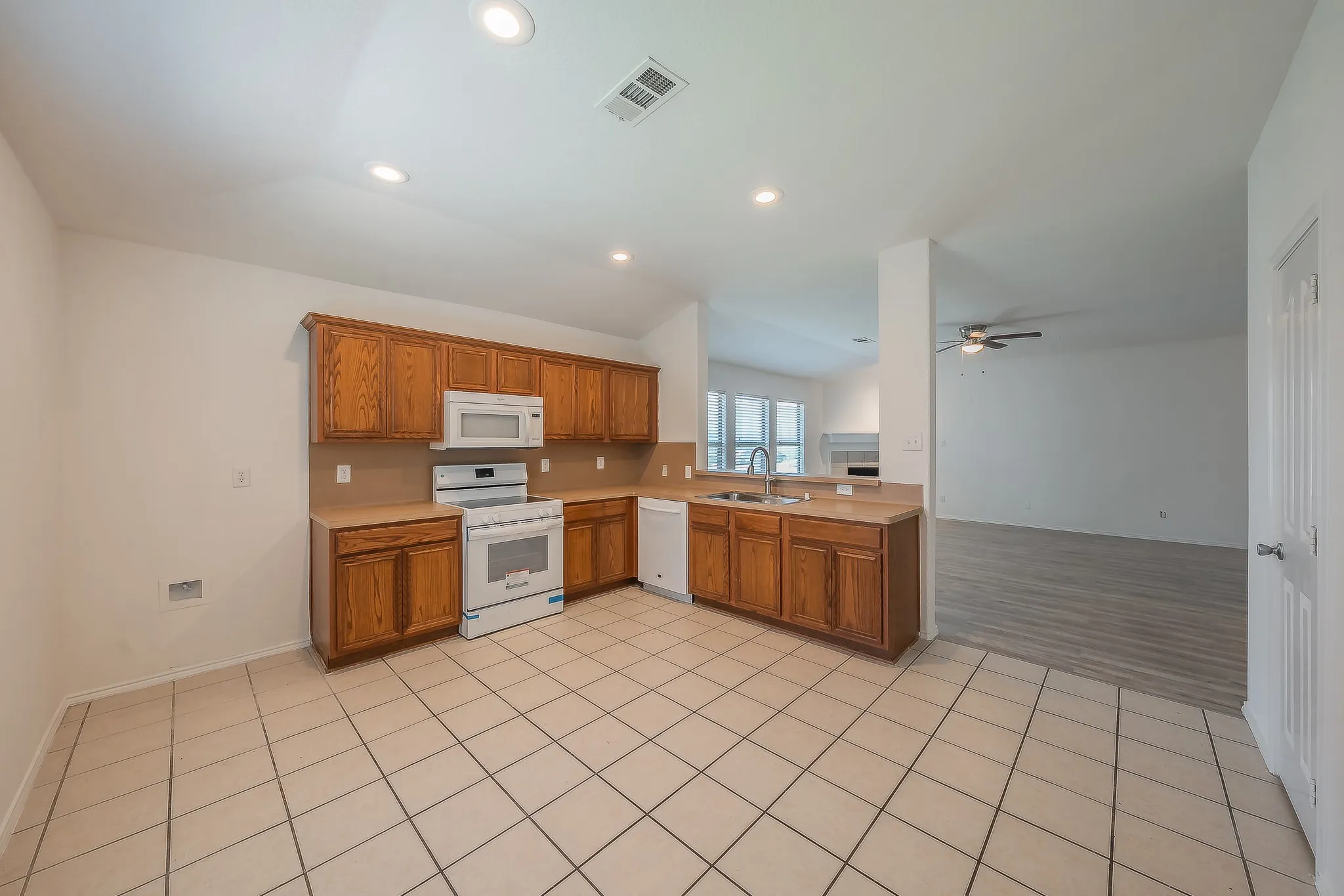 Kitchen featuring wood cabinetry, white appliances, recessed lighting, and tile flooring