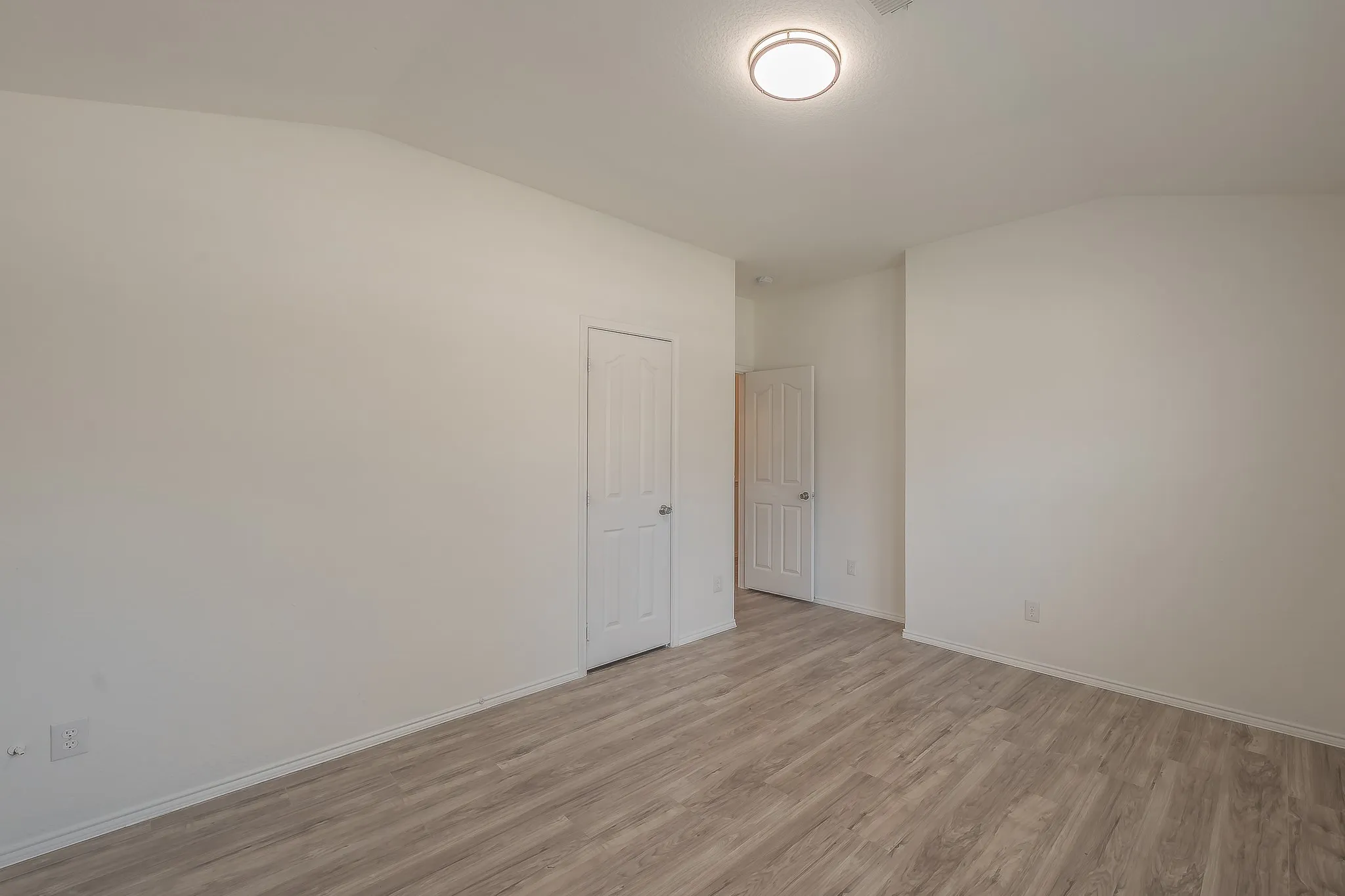 Recessed ceiling light, wood-finish flooring, white paneled doors, and white walls