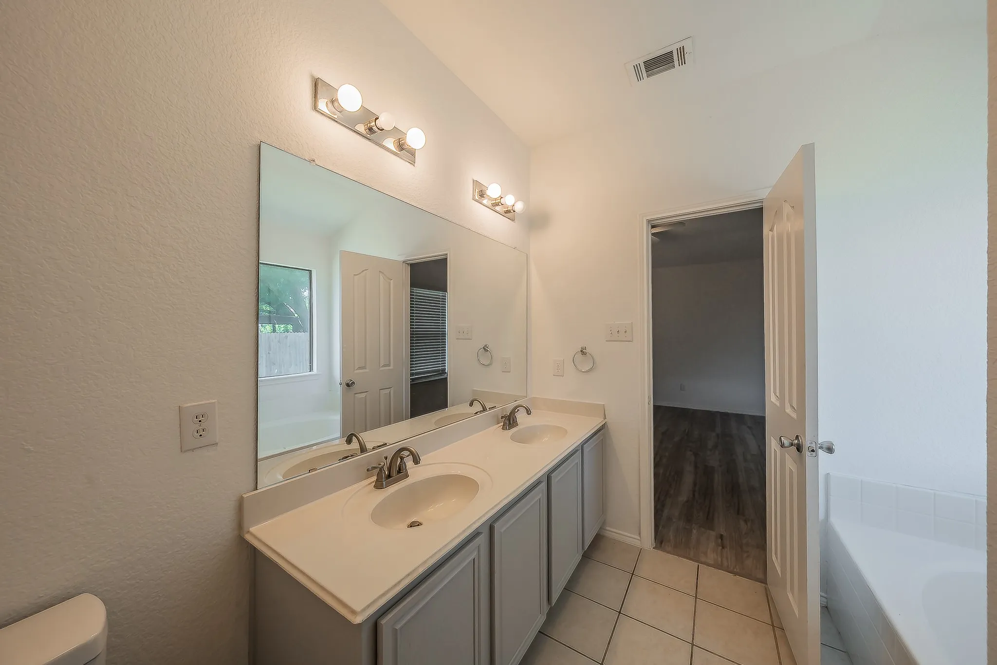 Dual vanity with integrated sinks, brushed nickel faucets, and a large wall-mounted mirror