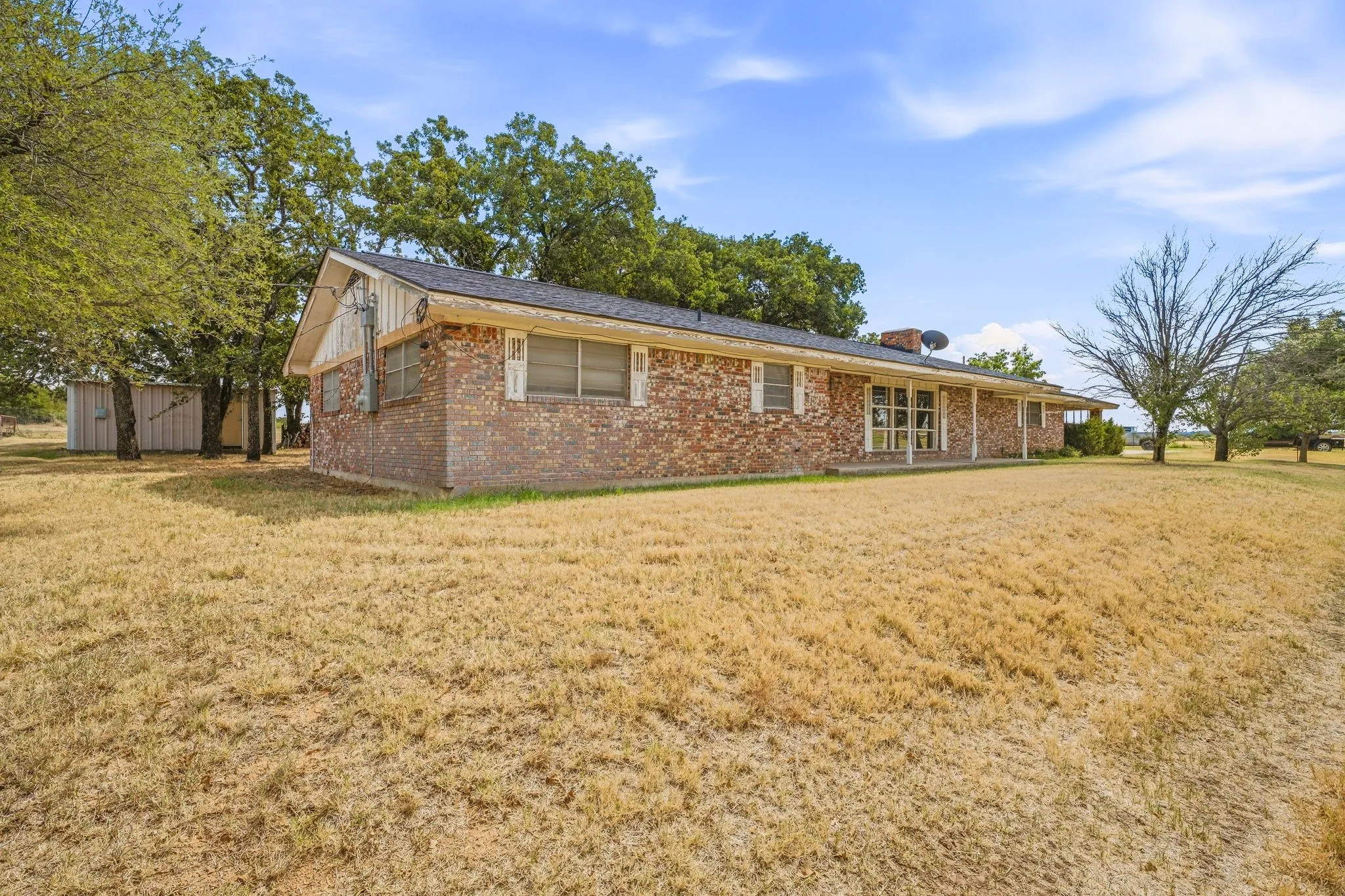Brick exterior with a covered front porch, white window shutters, and a dark shingle roof