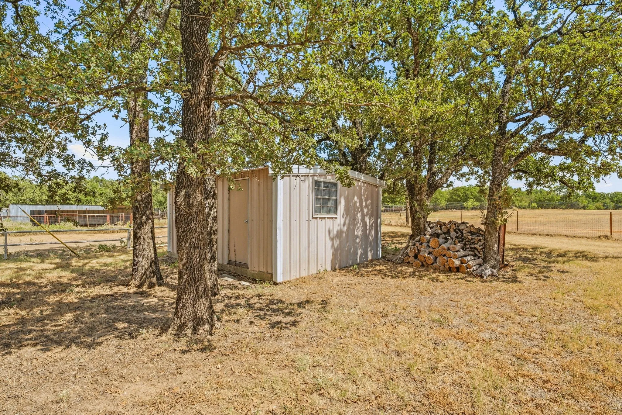 Detached utility shed with a single window, surrounded by mature trees