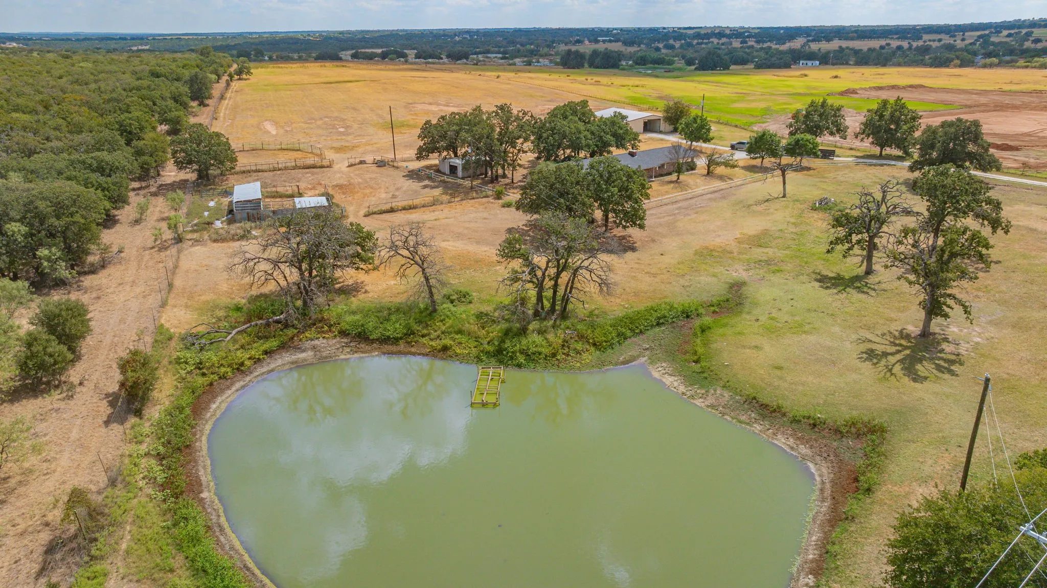 Private pond with surrounding natural landscape, mature trees, and agricultural land
