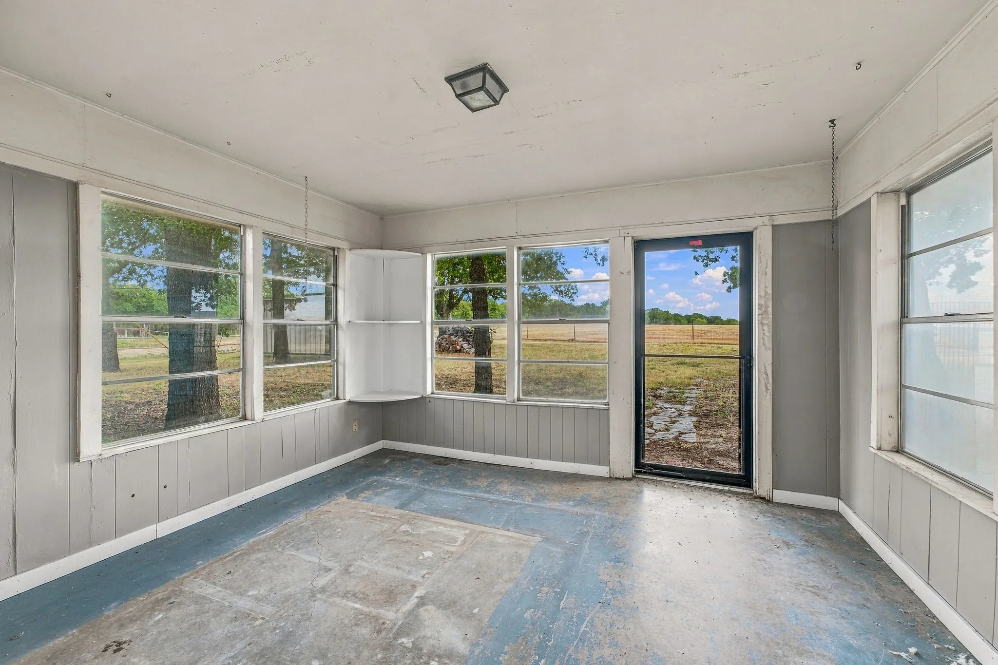Enclosed porch featuring multiple windows, a full-light exterior door, and a built-in corner shelf