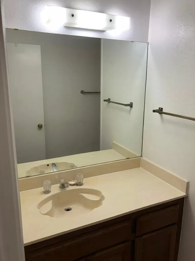 Integrated vanity with an oval basin, wood-finish cabinetry, and a large mirror