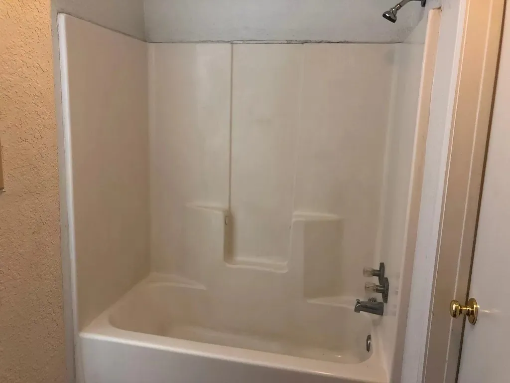 Bathtub and shower combination unit with integrated shelving and wall-mounted showerhead