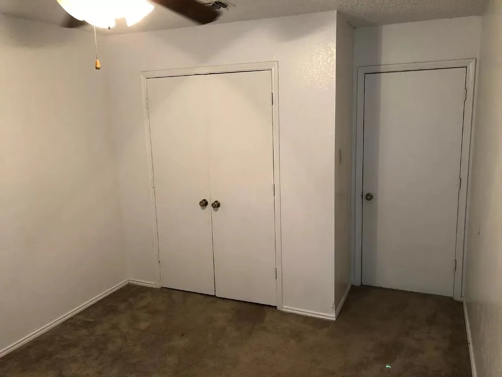 Carpeted flooring with painted walls, a ceiling fan with integrated lighting, and white bi-fold closet doors