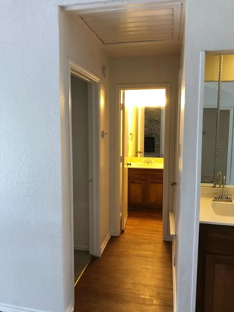 Hallway featuring wood-finish flooring, white walls, and an attic access panel