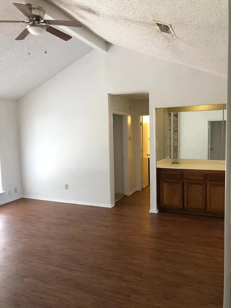 Vaulted ceiling with a ceiling fan, wood-finish flooring, and built-in cabinetry with a countertop