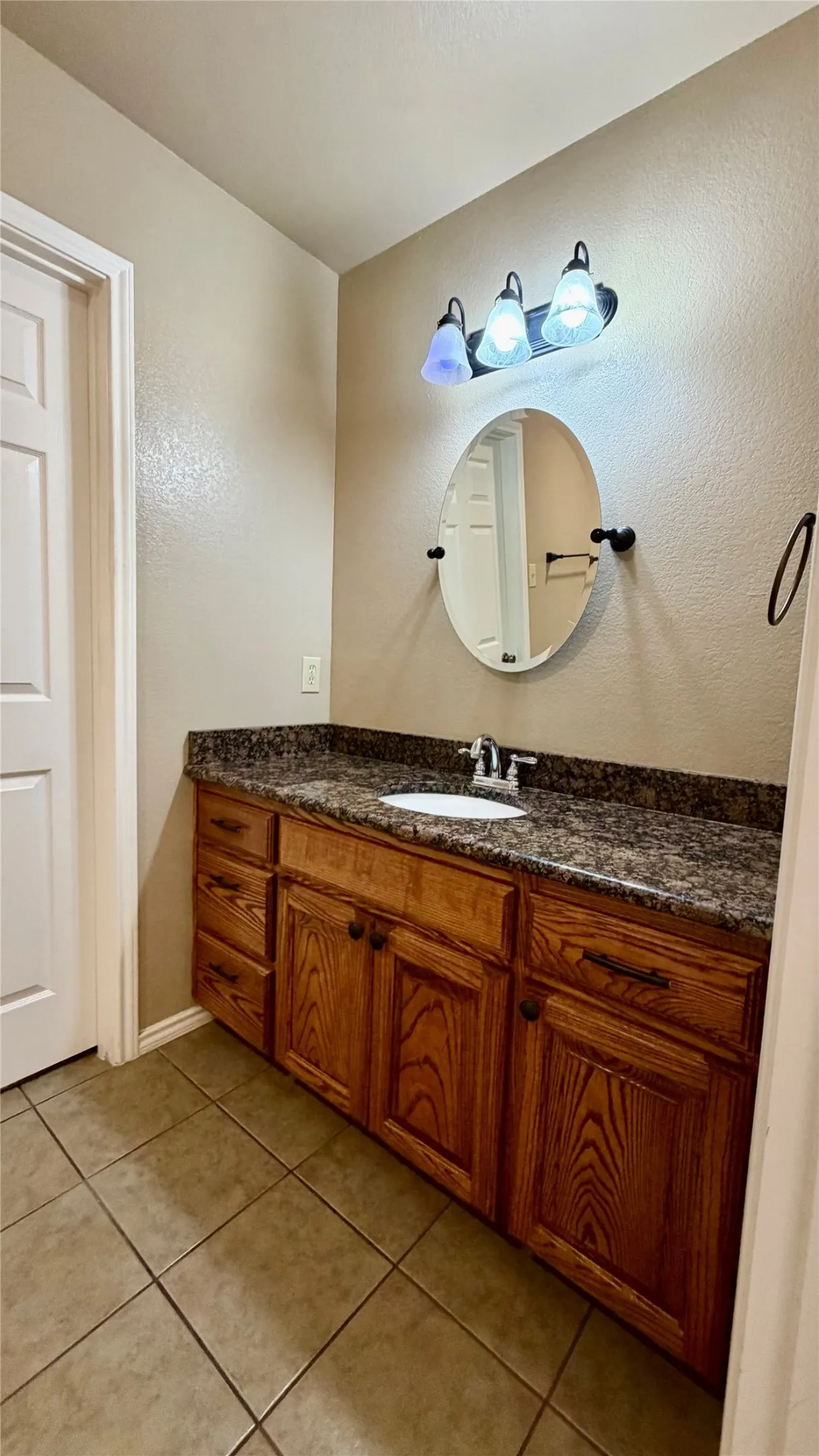 Tile flooring with a wood-finish vanity featuring dual cabinet storage and drawer space