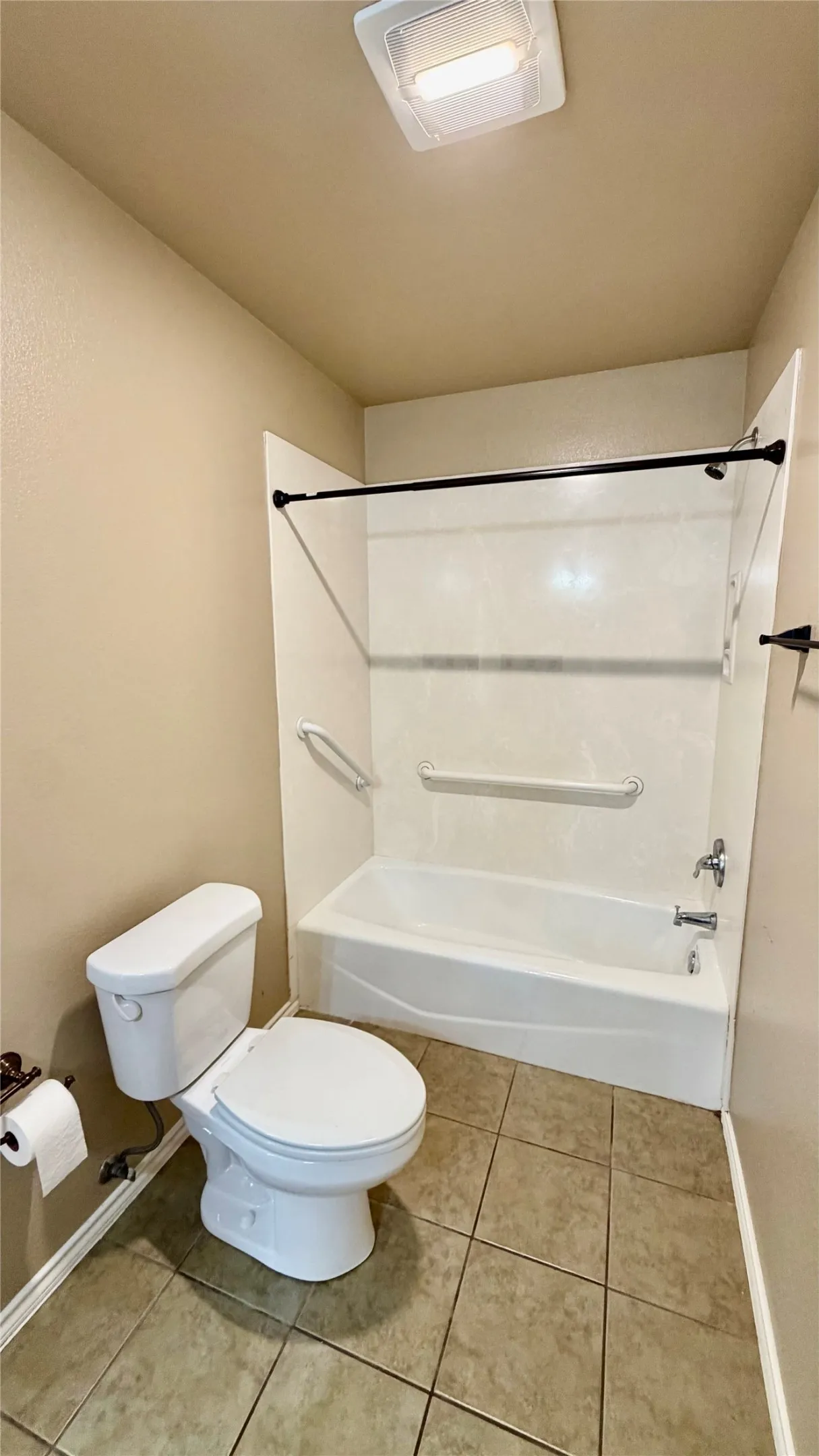 Tub and shower combination with white surround, grab bars, and a black shower curtain rod