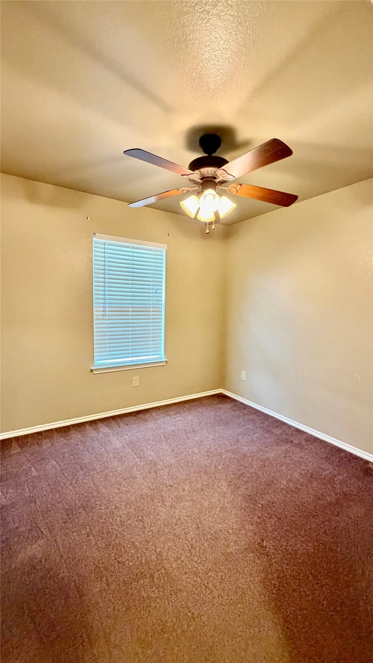 Ceiling fan with integrated lighting, window with horizontal blinds, wall-to-wall carpeting