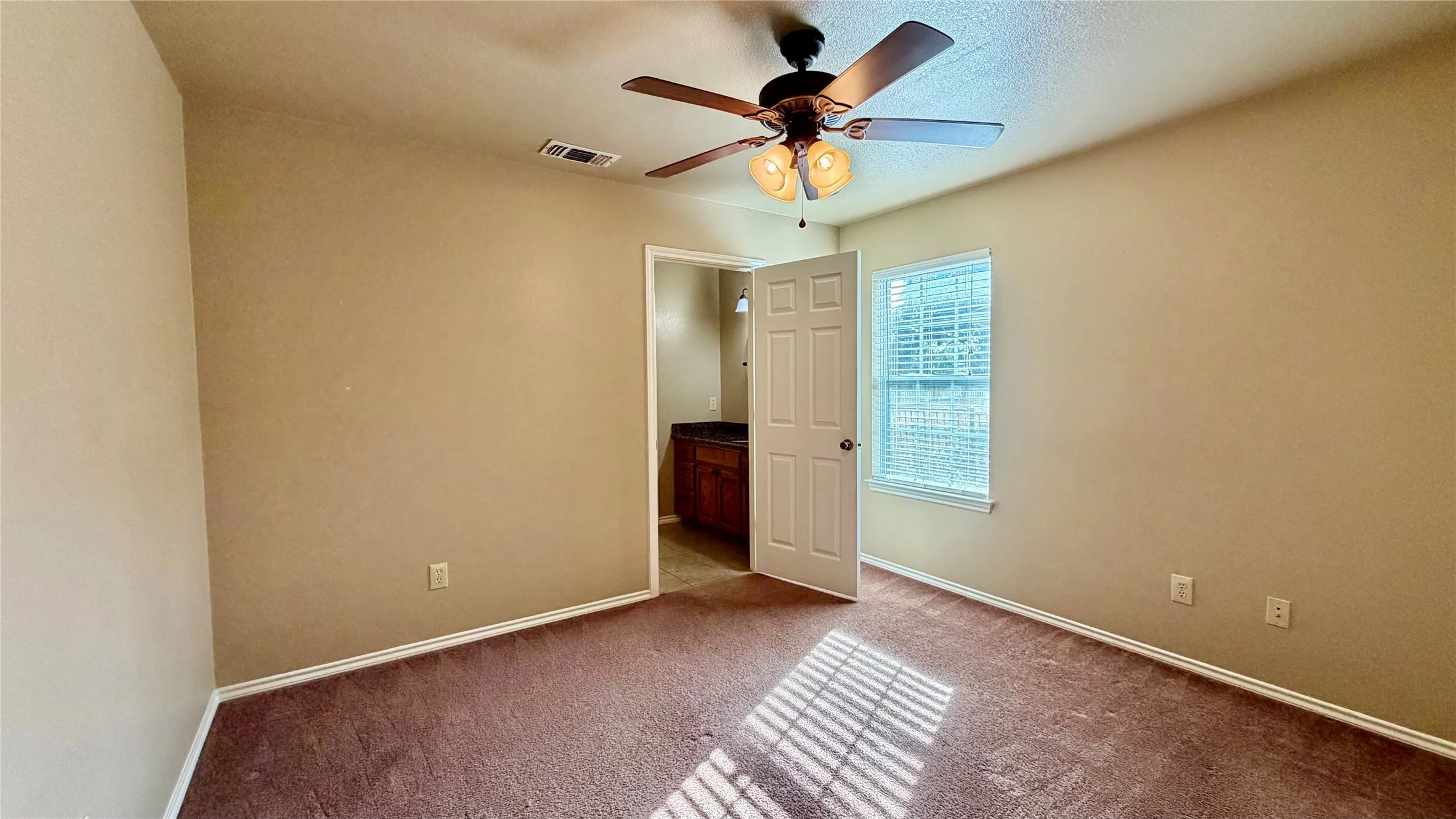 Recessed window featuring horizontal blinds, ceiling fan with integrated lighting, and a wood-finish vanity with a dark​​‌​​​​‌​​‌‌​‌‌​​​‌‌​‌​‌​‌​​​‌​​ countertop