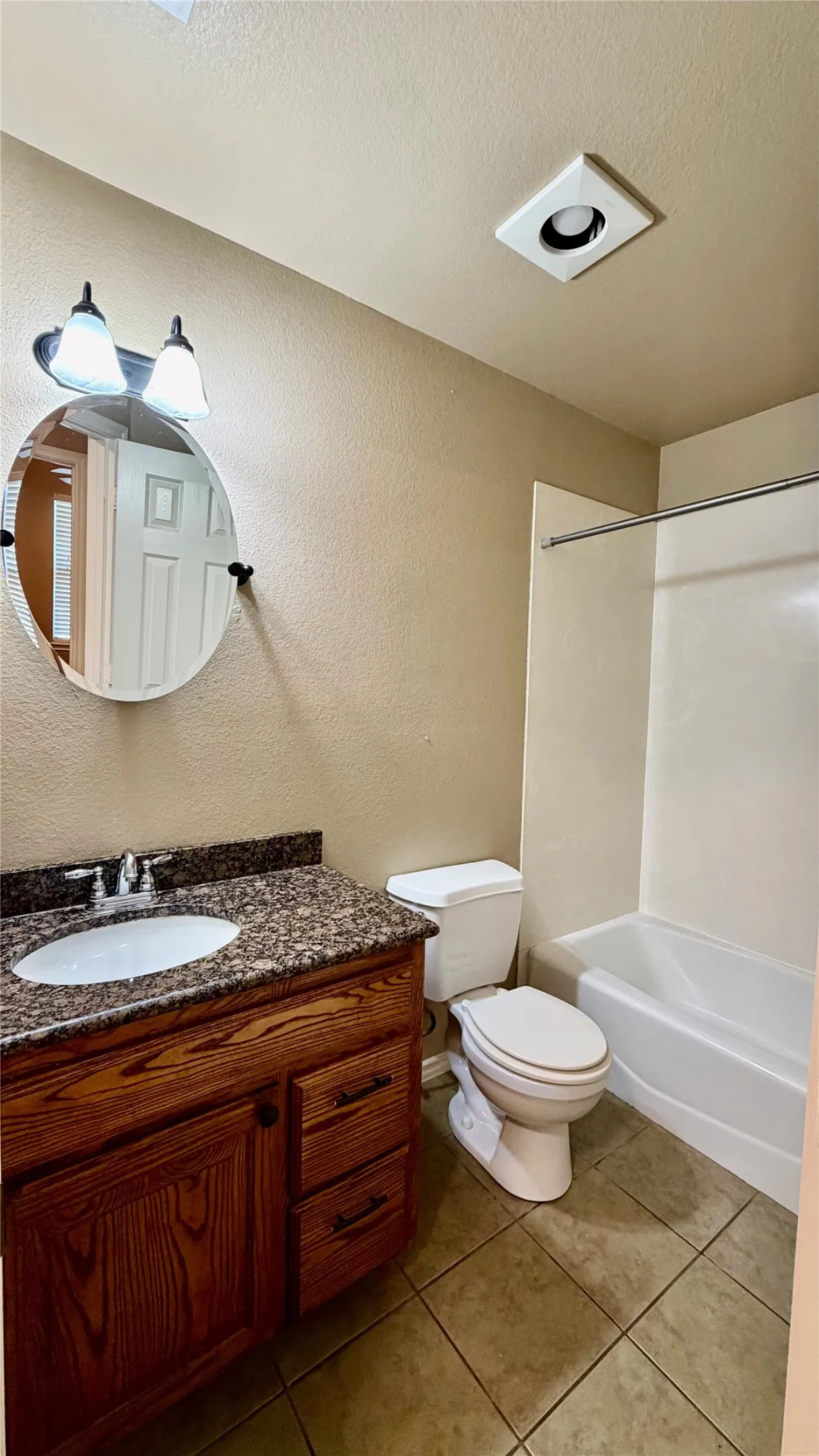 Wood-finish vanity with an integrated sink, polished chrome faucet, and speckled countertop