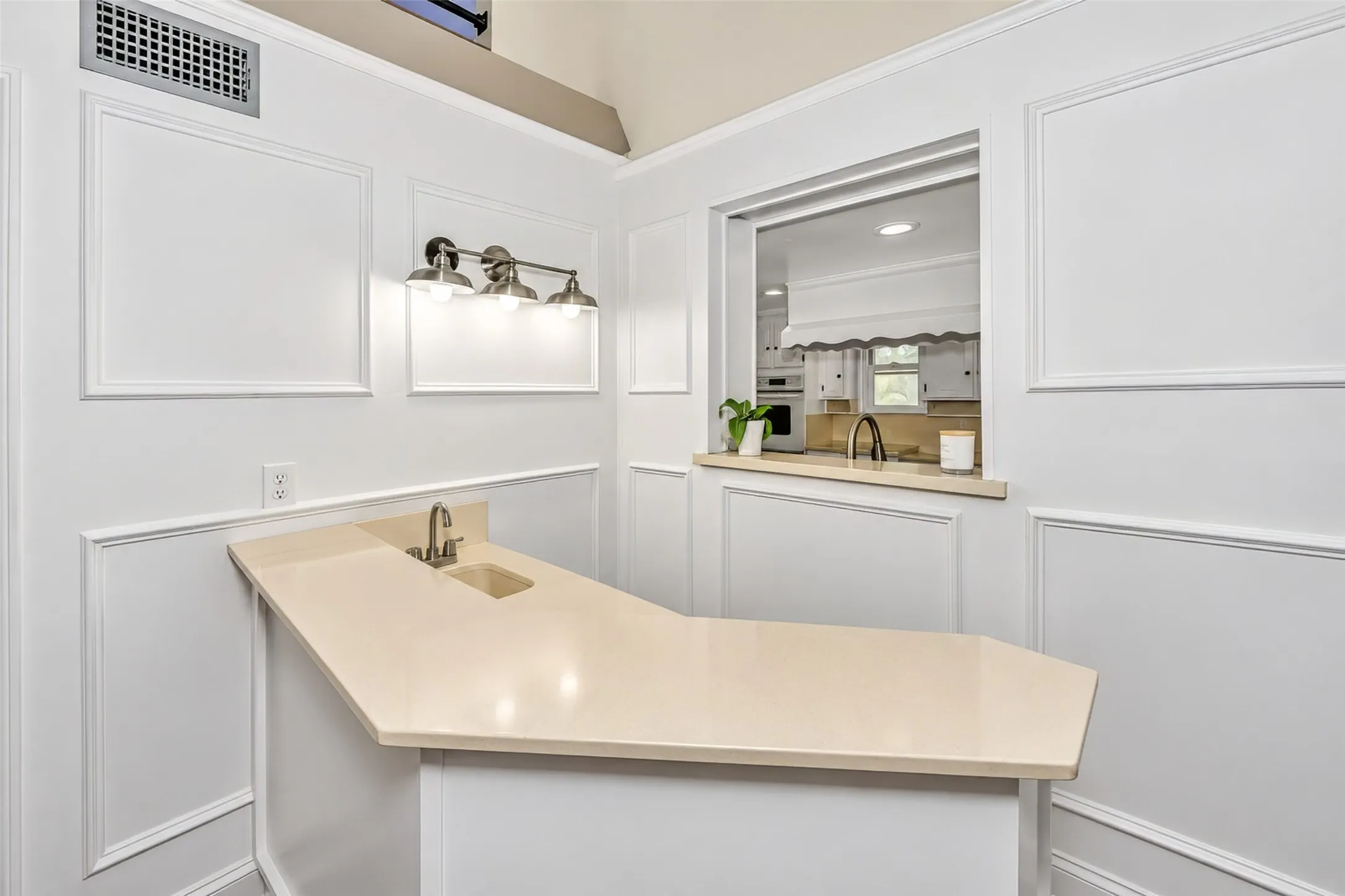 Angled counter with integrated sink, brushed nickel faucet, and neutral countertop