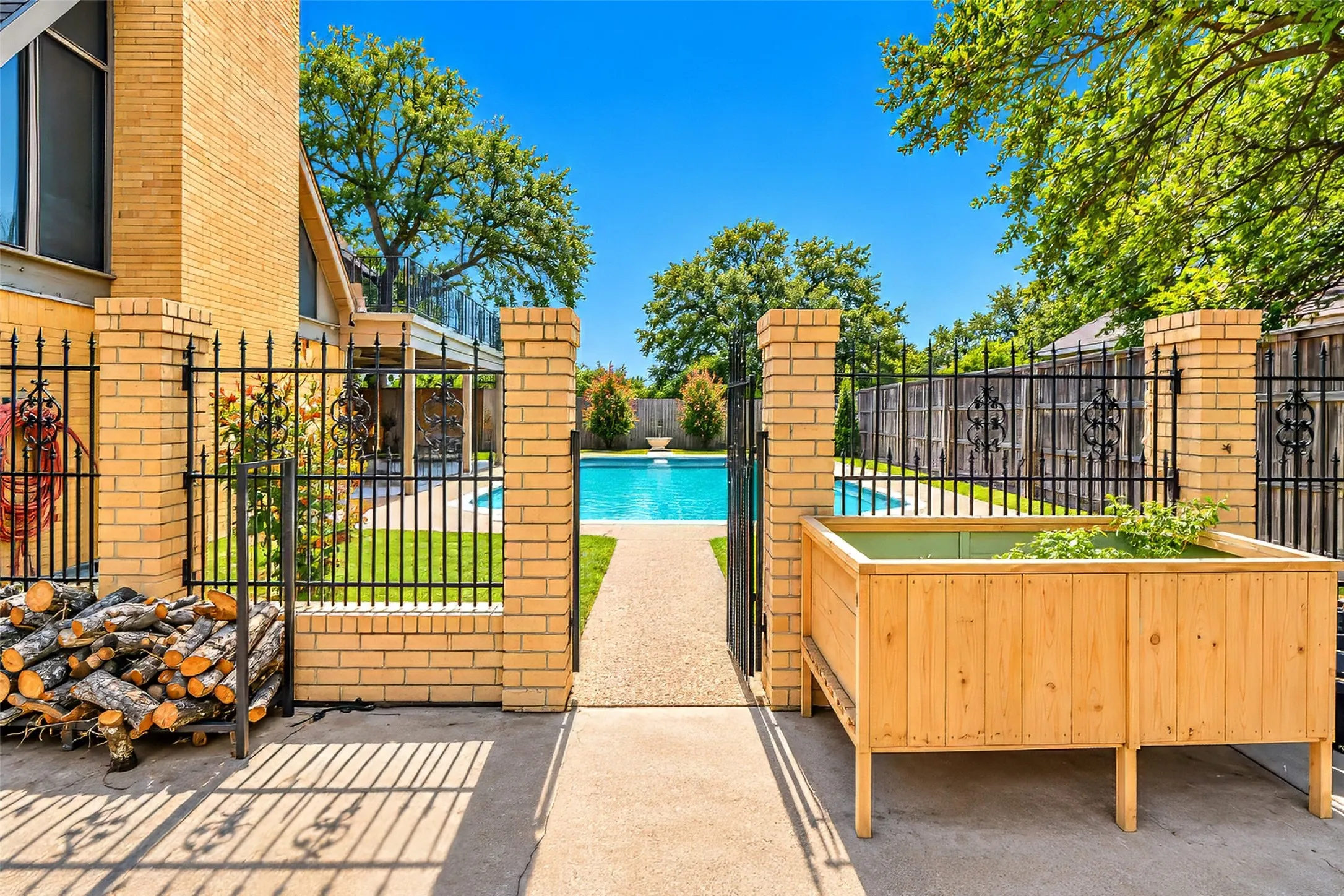 Brick columns with wrought iron fencing, a paved pathway, and a built-in pool