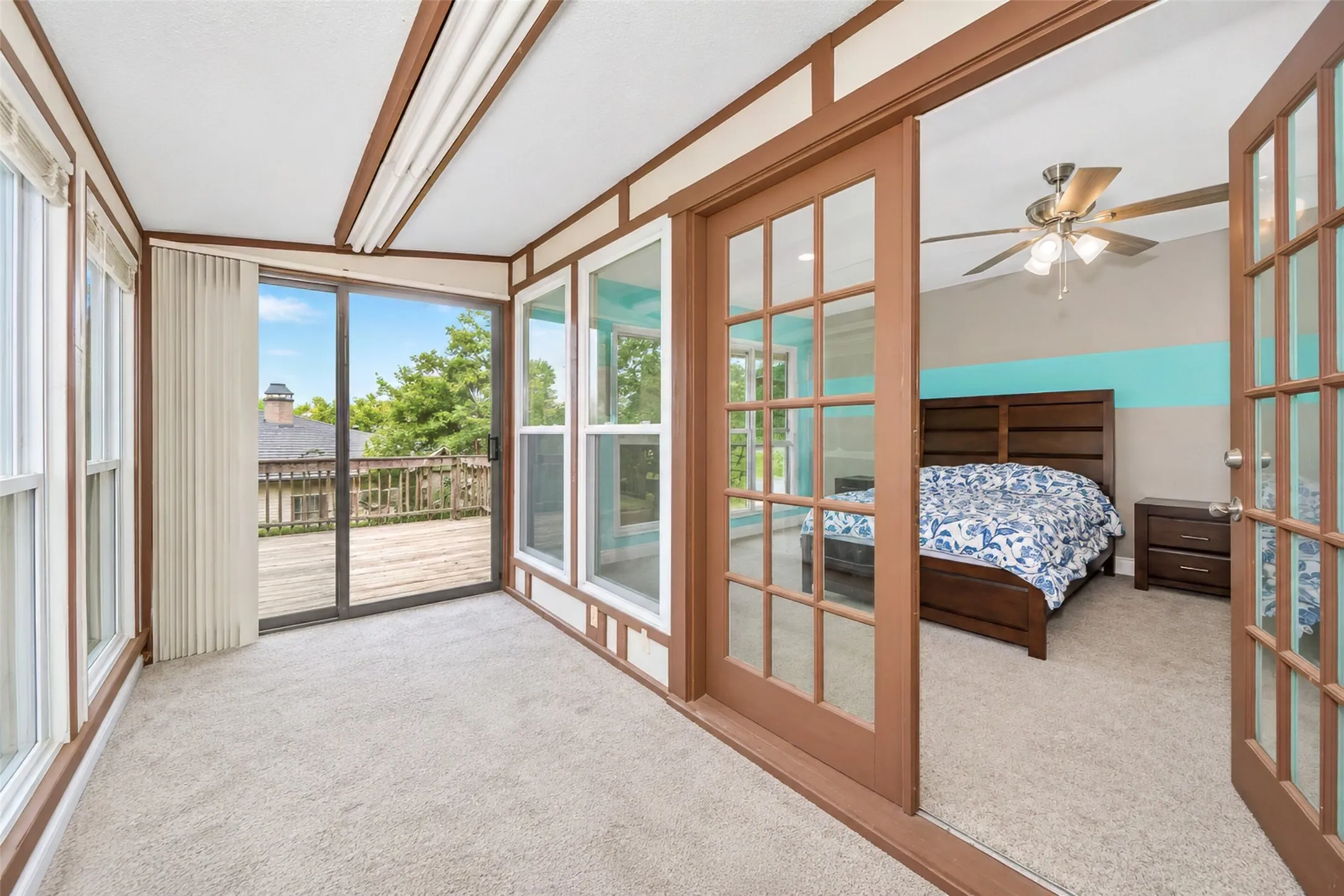 Sunroom with carpet flooring, extensive window placements, and a sliding glass door opening to an outdoor wood deck