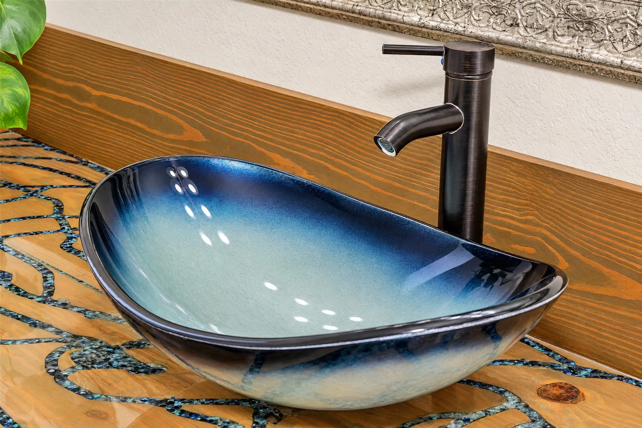 Vessel sink with a blue-to-white gradient finish, bronze-tone faucet, and wood-finish countertop with inlaid detailing