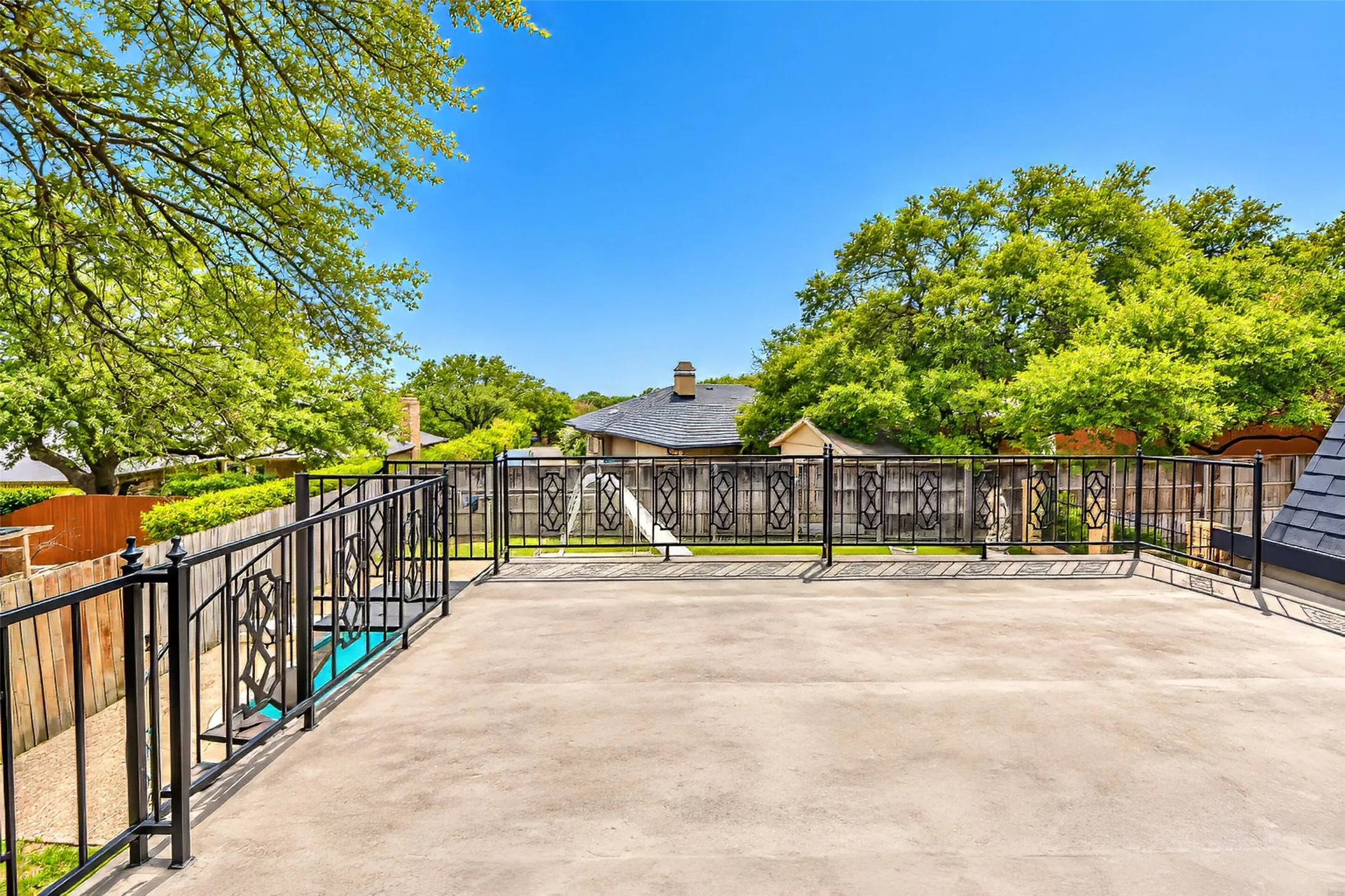 Expansive concrete rooftop terrace with ornamental metal railings