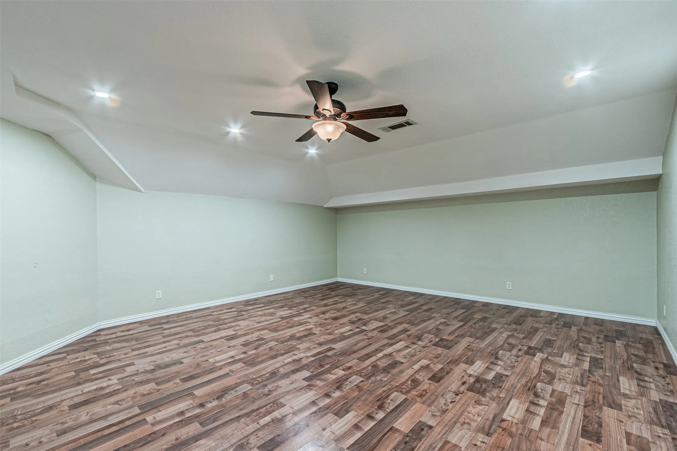 Wood-finish flooring with light green walls, recessed lighting, and a ceiling fan