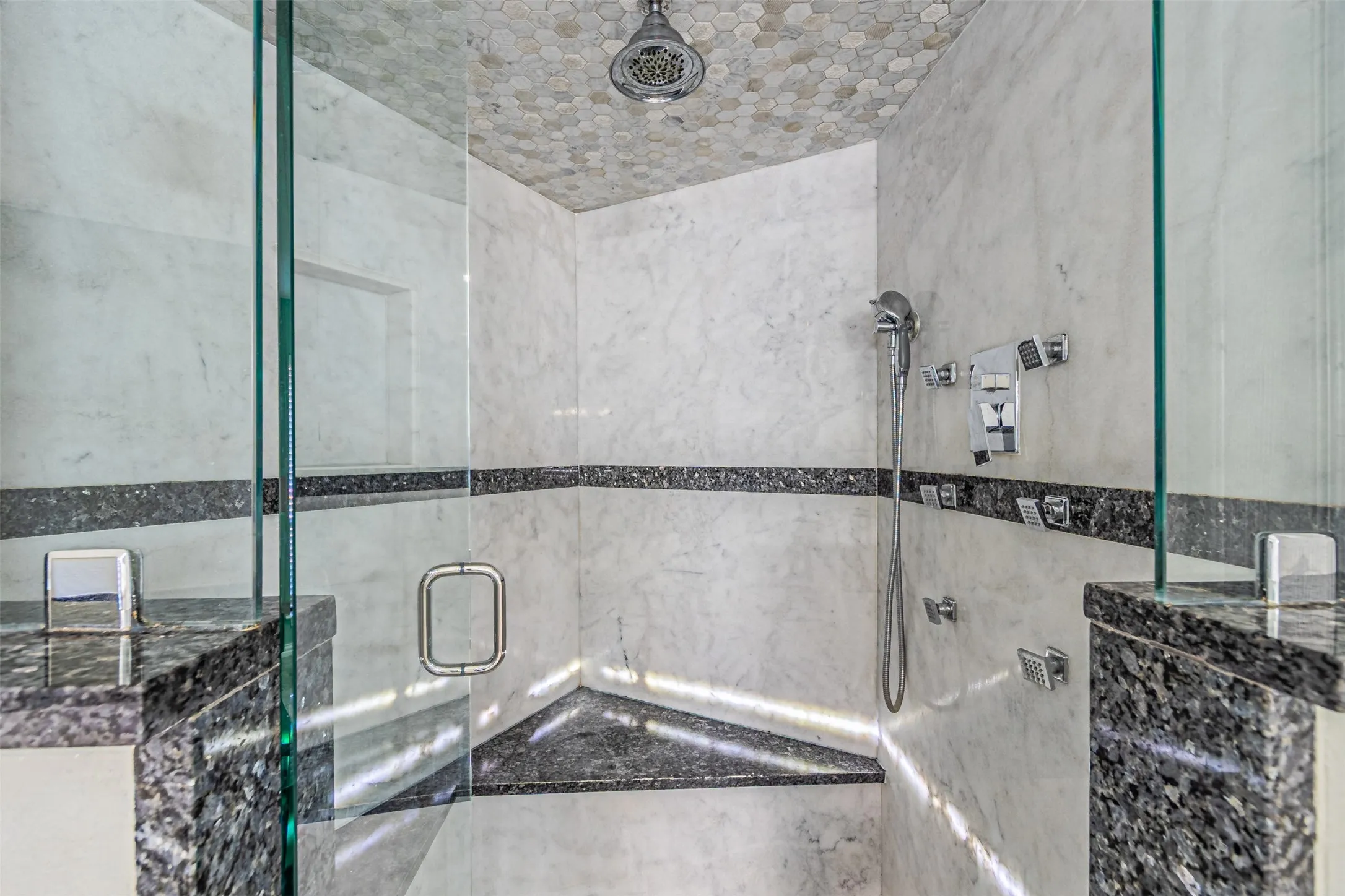 Glass-enclosed shower featuring a tiled ceiling, a built-in corner bench, and a built-in shower niche