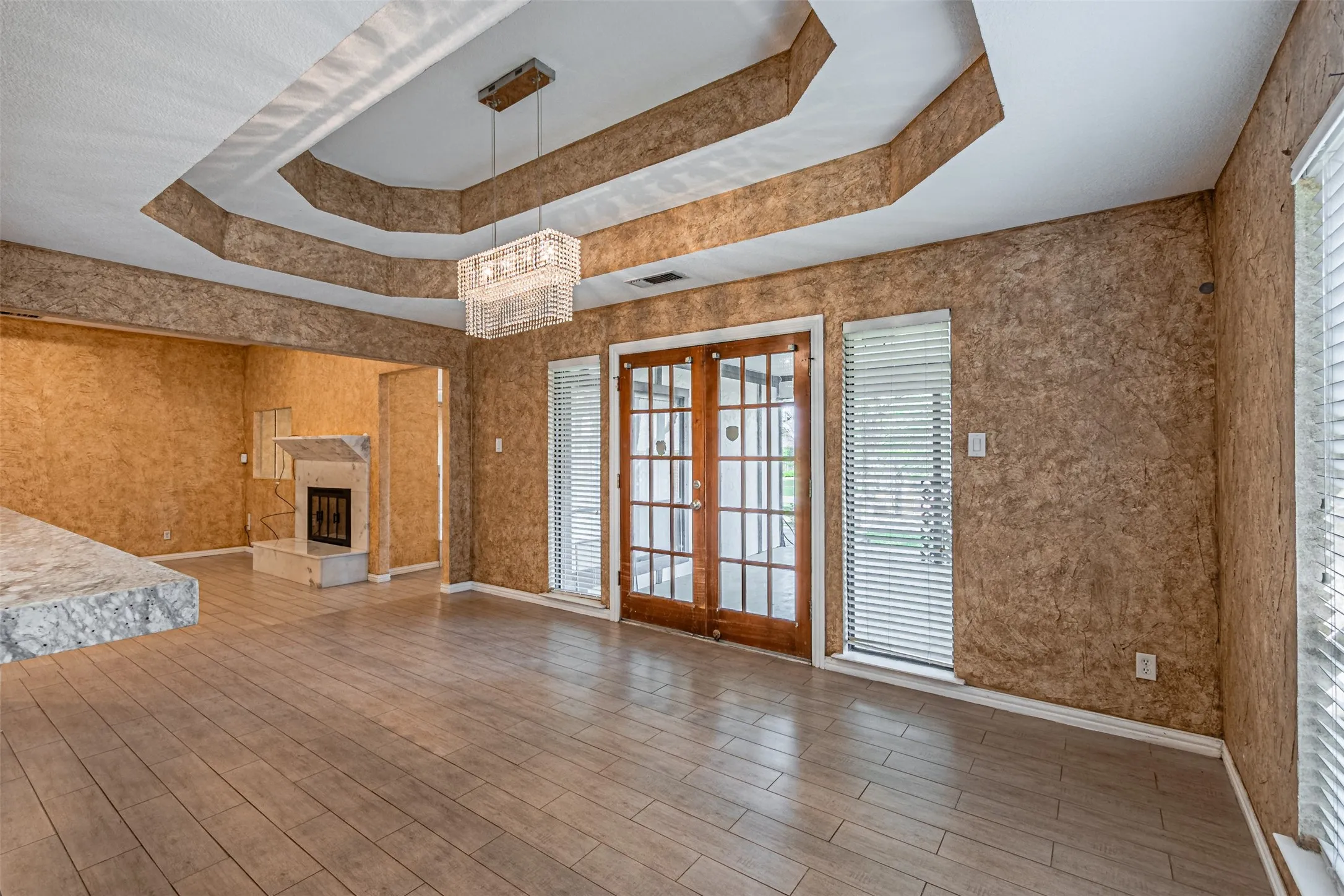 Tray ceiling with recessed lighting, wood-finish flooring, built-in fireplace, and double French doors
