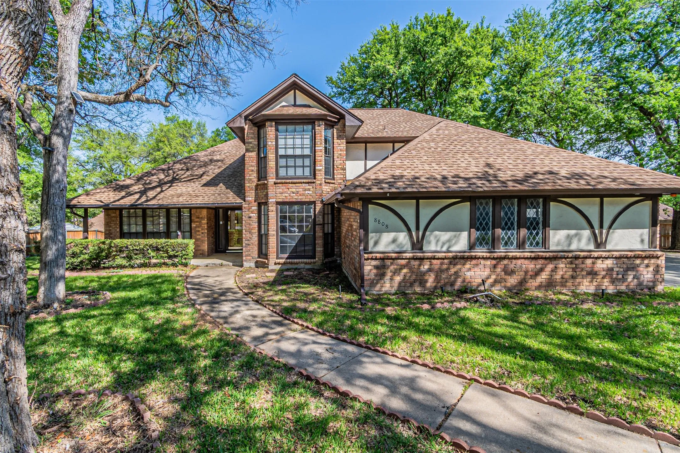 Brick exterior with a prominent bay window, gabled roofline, and an inviting pathway