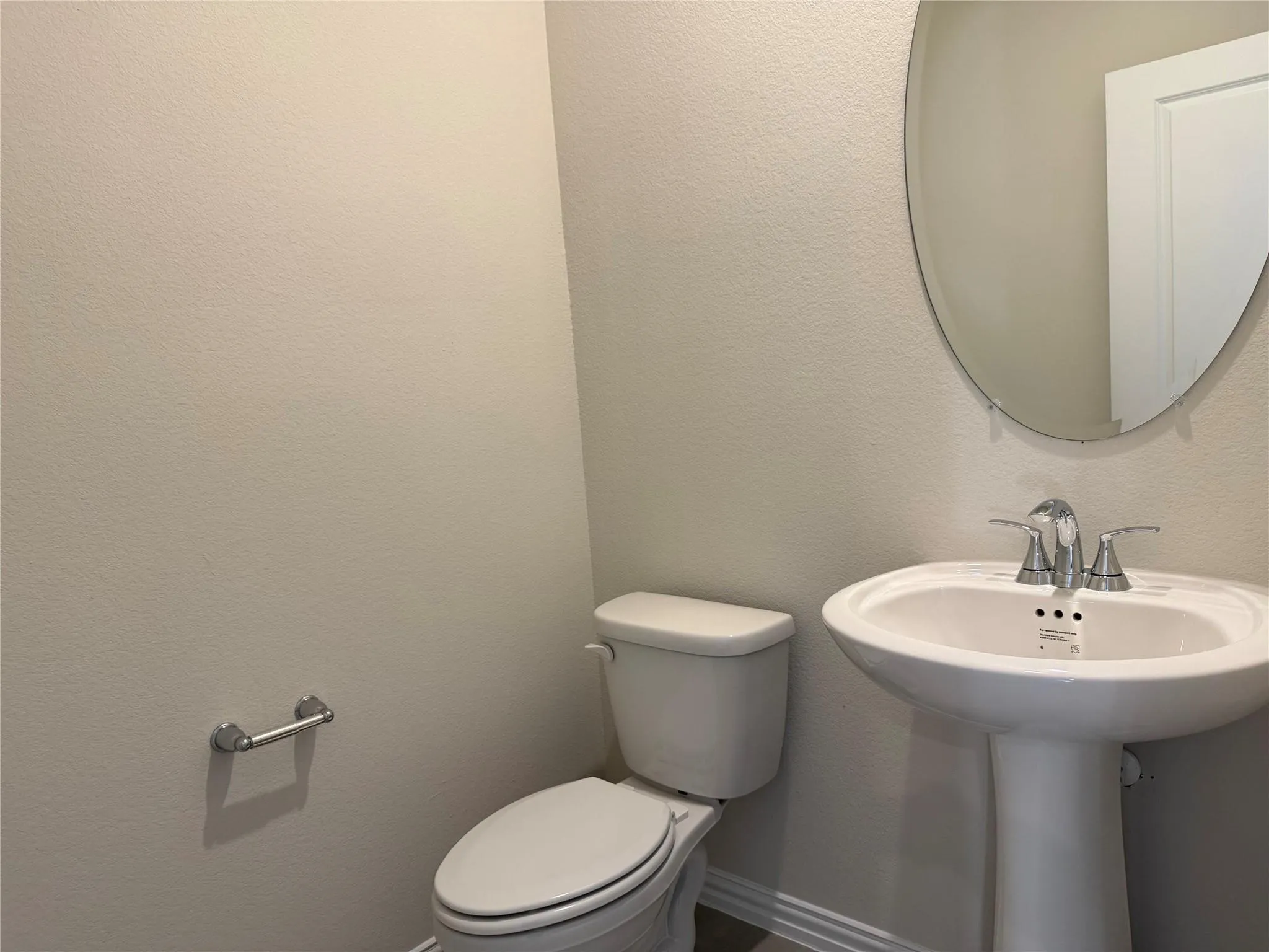 Pedestal sink with chrome-finish faucet and an oval wall mirror