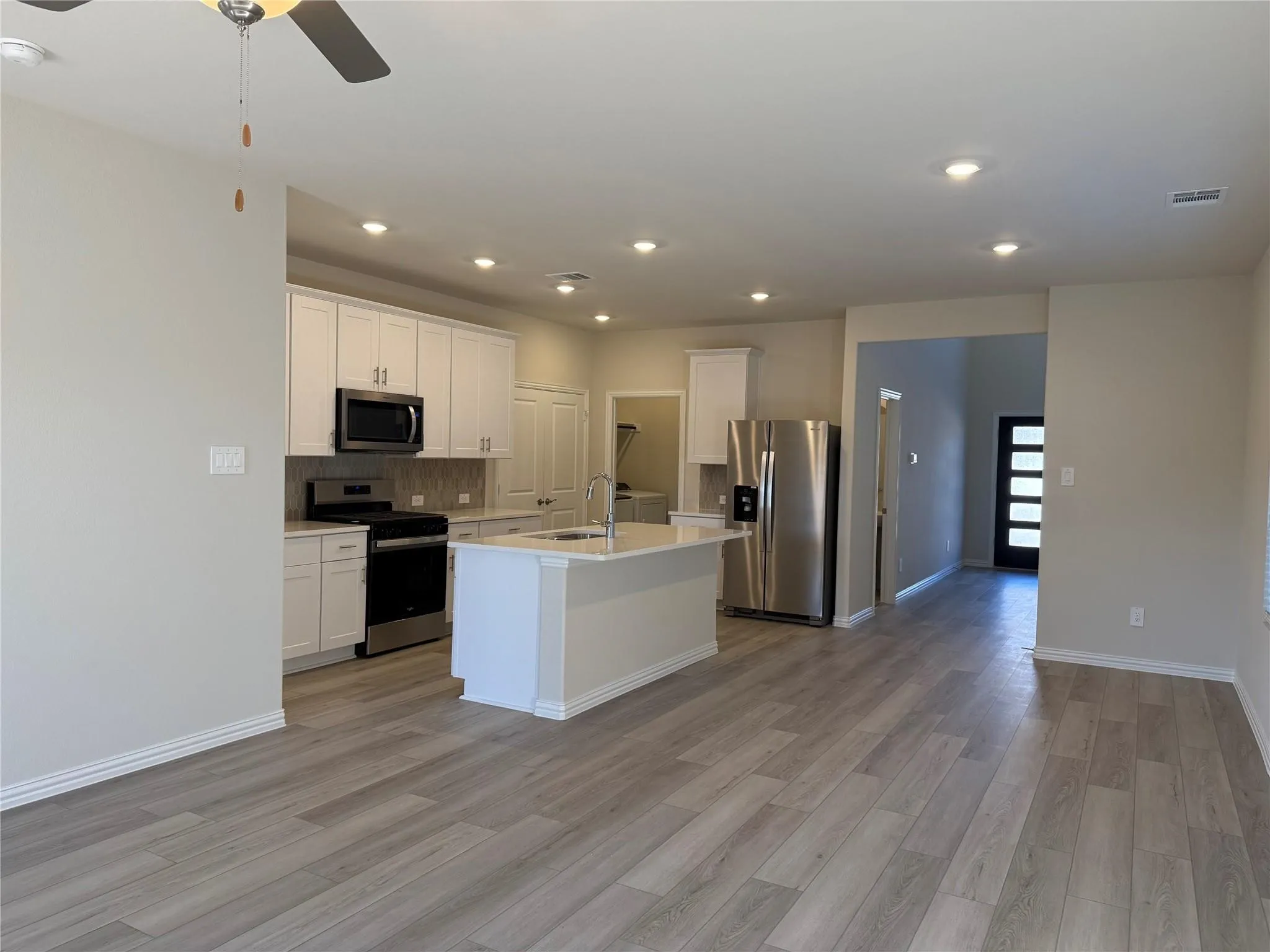 Open-concept living space with wood-finish flooring, recessed lighting, and a ceiling fan