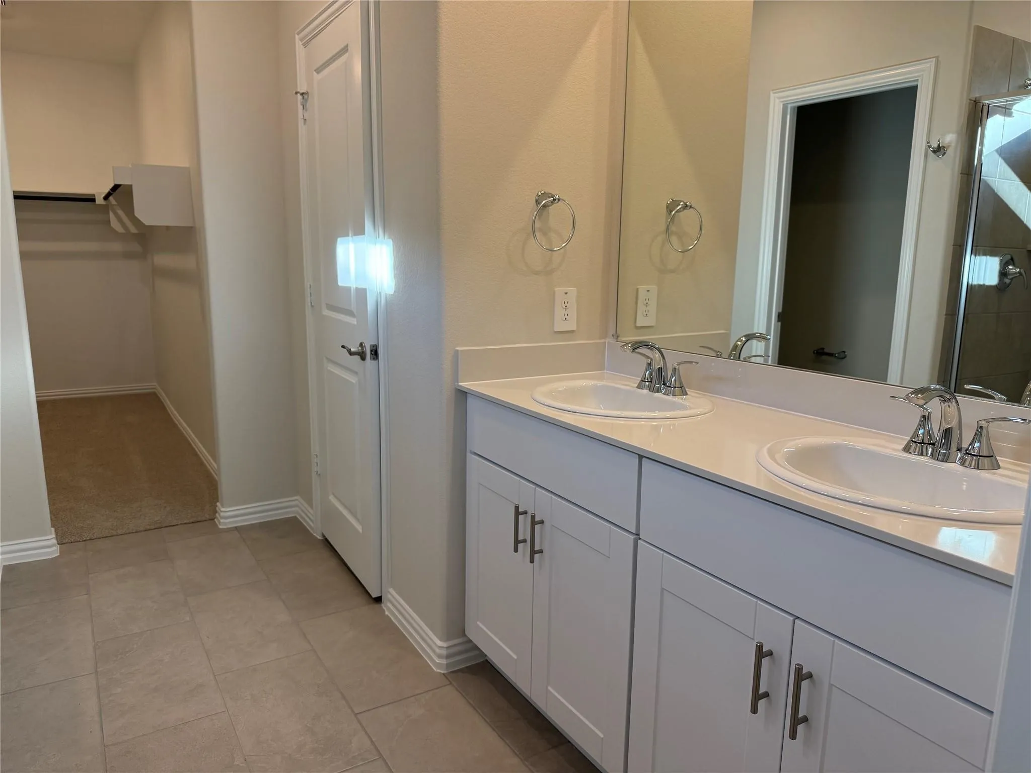 Double vanity with white cabinetry, polished chrome fixtures, and integrated sinks