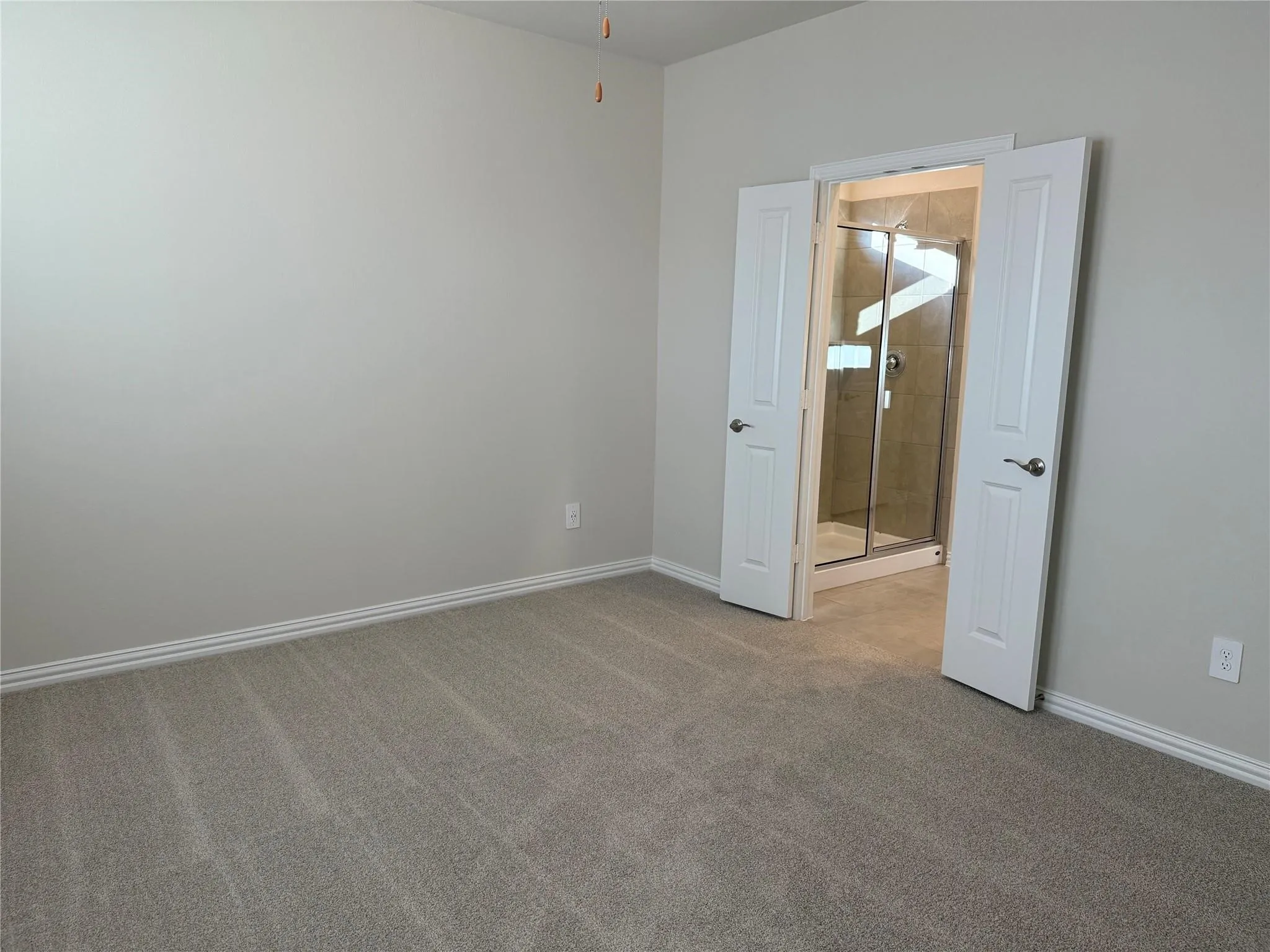 Spacious bedroom with neutral wall finishes, plush carpet flooring, and double closet doors with white frames