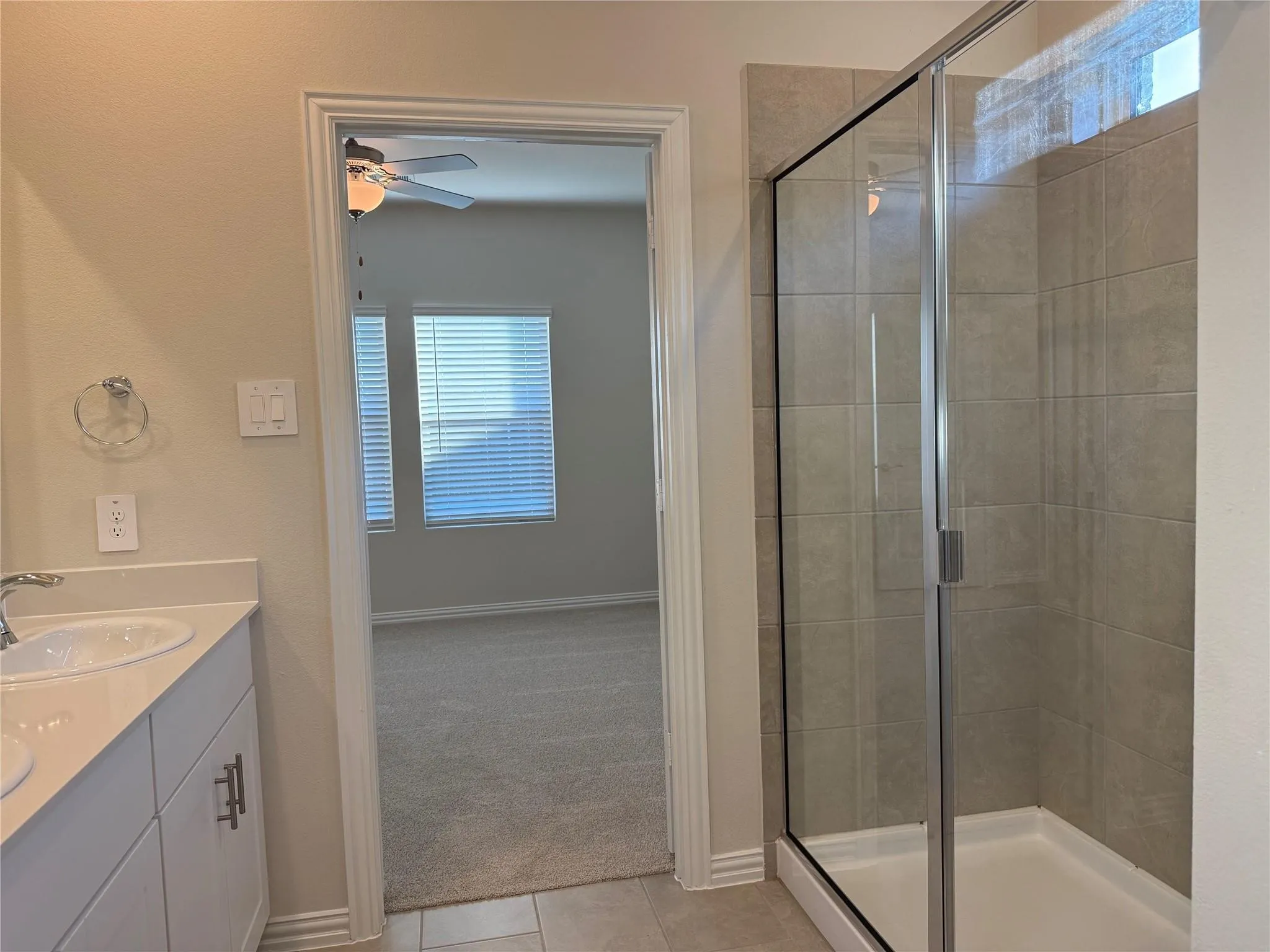 Walk-in shower with clear glass enclosure and light-toned tile surround