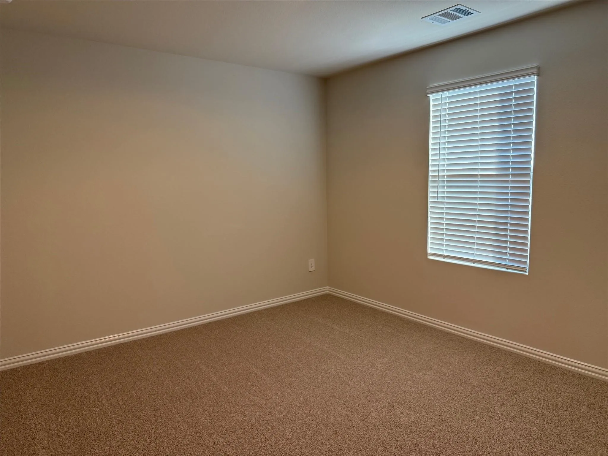 Carpeted flooring, neutral wall paint, window with blinds, ceiling-mounted vent