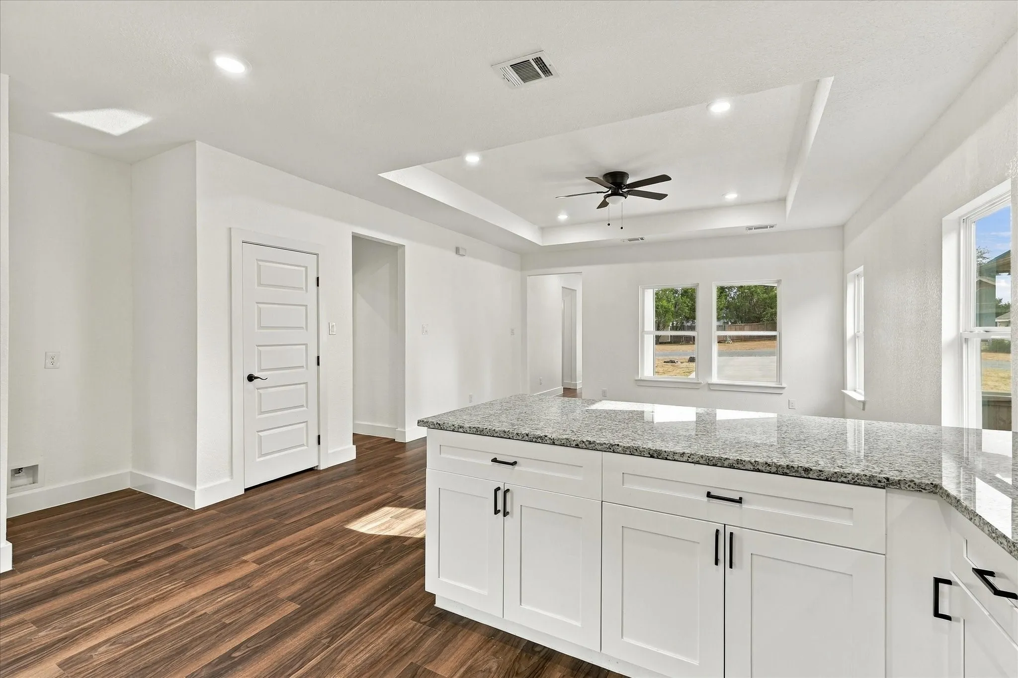 Kitchen island with stone countertop, white shaker cabinetry, and dark hardware