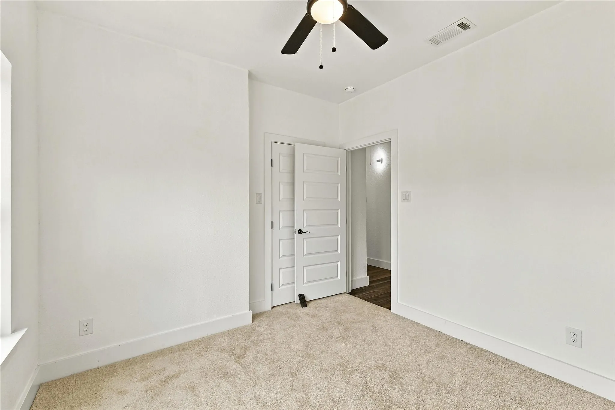 Carpeted room with white walls, a ceiling fan, and a flat-panel interior door