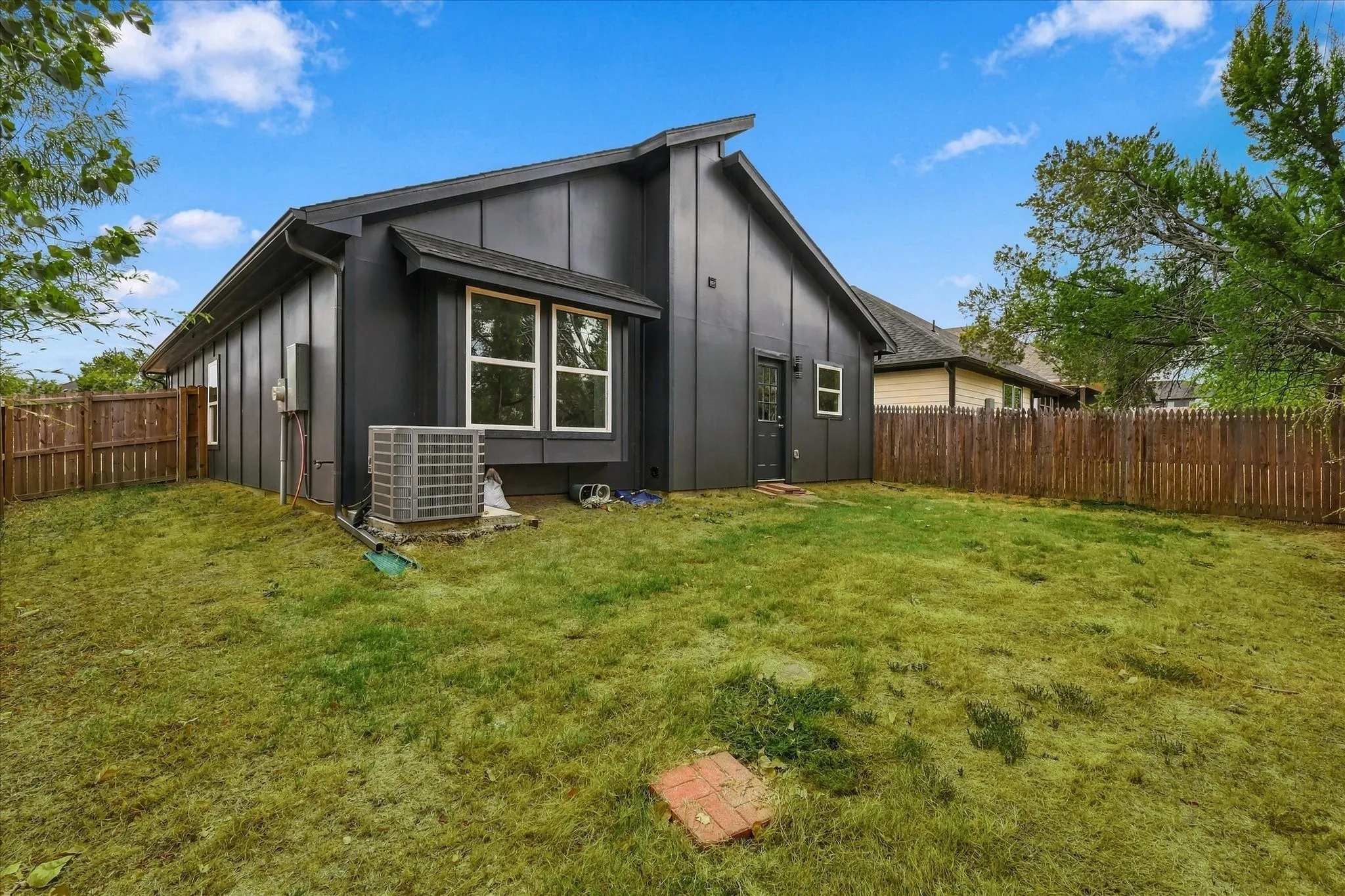 Expansive backyard featuring a privacy fence, contemporary exterior siding, and multiple windows