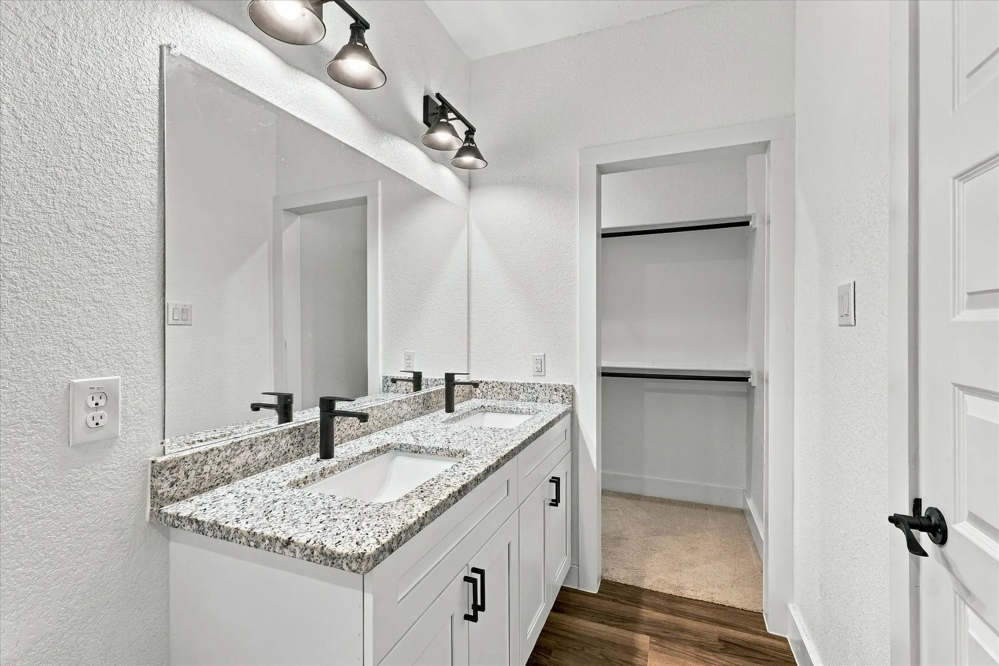 Dual vanity with granite countertops, undermount sinks, and matte black fixtures