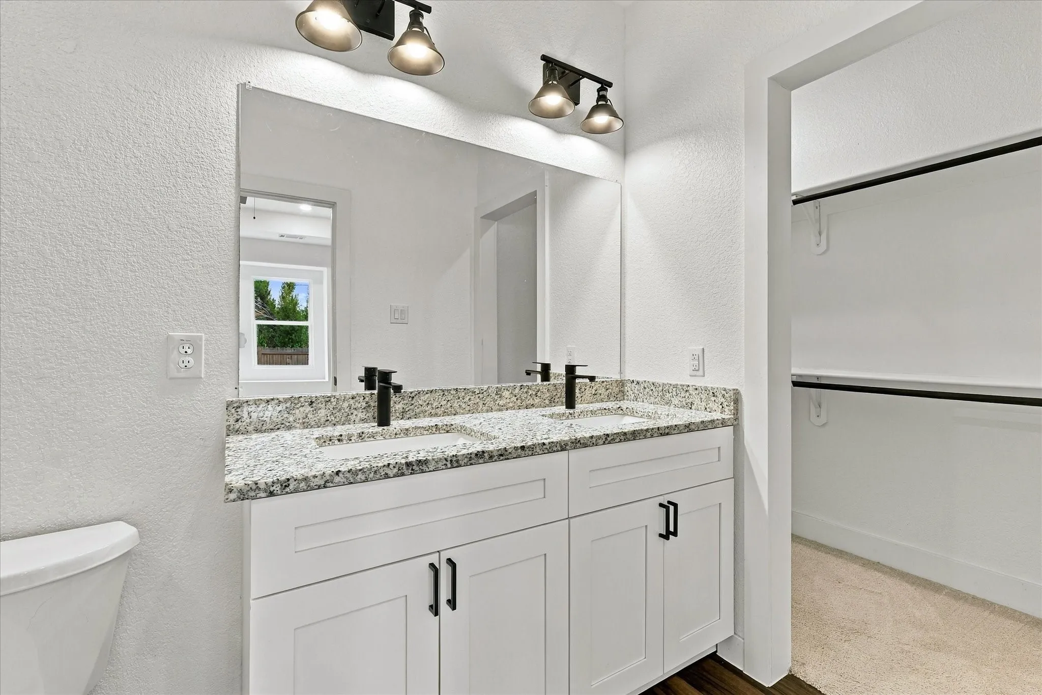Dual vanity with granite-style countertop, undermount sinks, and matte black fixtures