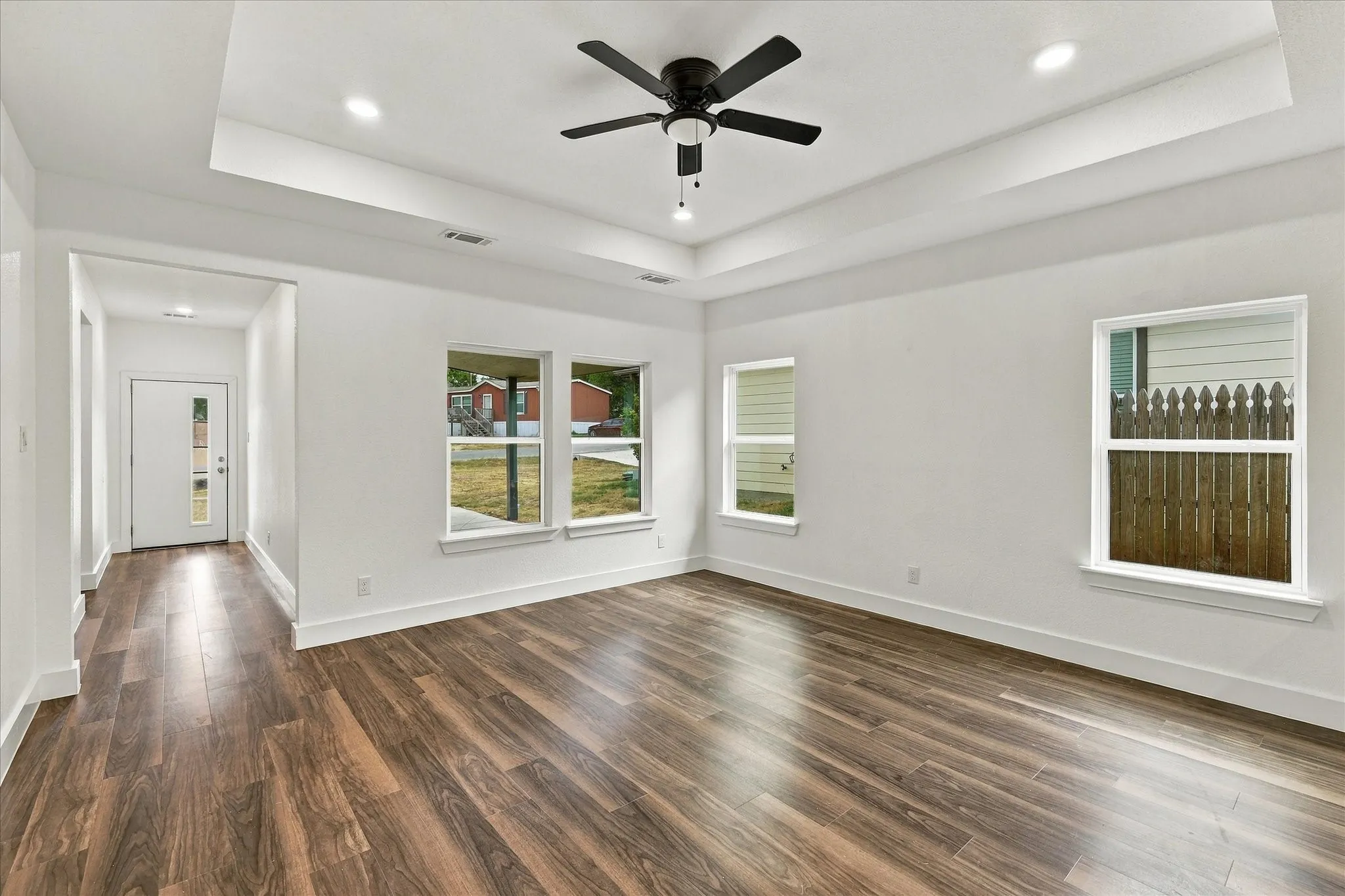 Recessed lighting and a tray ceiling complement wood-finish flooring