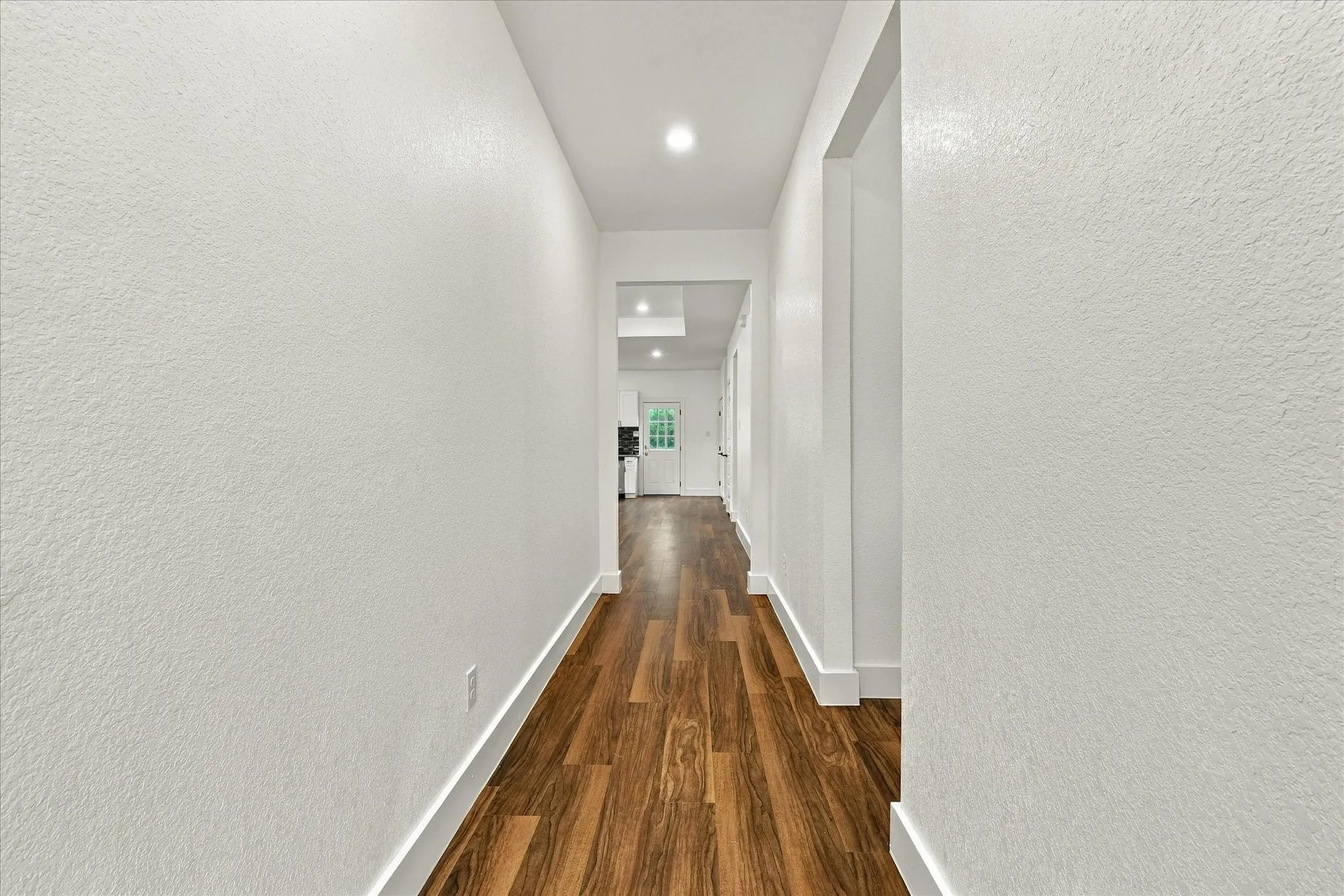 Hallway featuring wood-finish flooring, recessed lighting, and crisp white walls