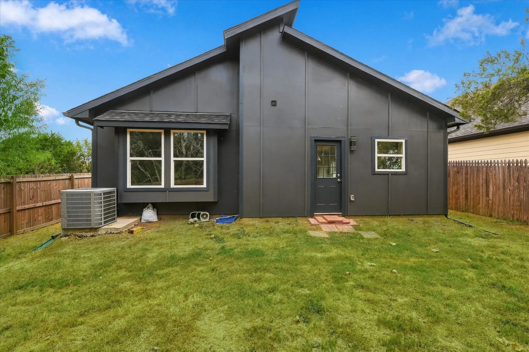 Rear exterior featuring dark vertical siding, a bay window, and a gabled roofline